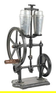HAND-CRANK DRINK/ MILKSHAKE MIXER: This early drink mixer is made of cast iron and holds two aluminum mixers at a time. When cranked, the machine oscillates the mixers back and forth. CONDITION: The cast iron body of the mixer has been