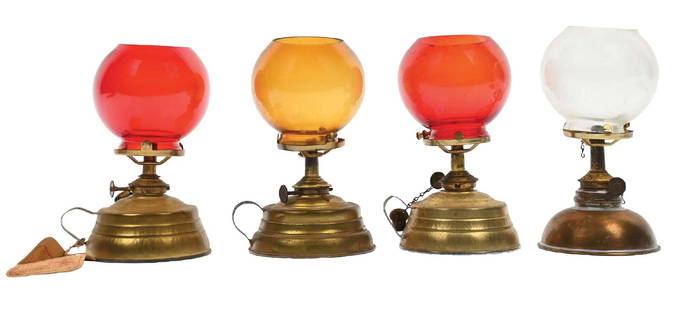 COLLECTION OF 4 COUNTERTOP CIGAR LIGHTERS: C. 1900. CONDITION: (A) A brass-base font with cranberry glass globe. (B) Another brass-base font with a clear glass globe. (C) A brass-base font with cranberry globe. (D) A brass-base font with amber