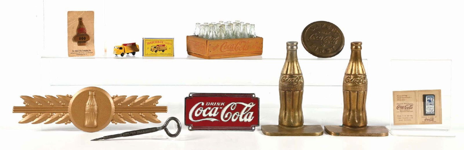 COLLECTION OF 10 VARIOUS COCA-COLA ADVERTISING ITEMS: This collection of ten advertising items from Coca-Cola includes a miniature 24-pack, brass bookends, sewing kit, small matchbox truck, ice pick, Kay Display frame plaque, delivery man bottle pin, sid