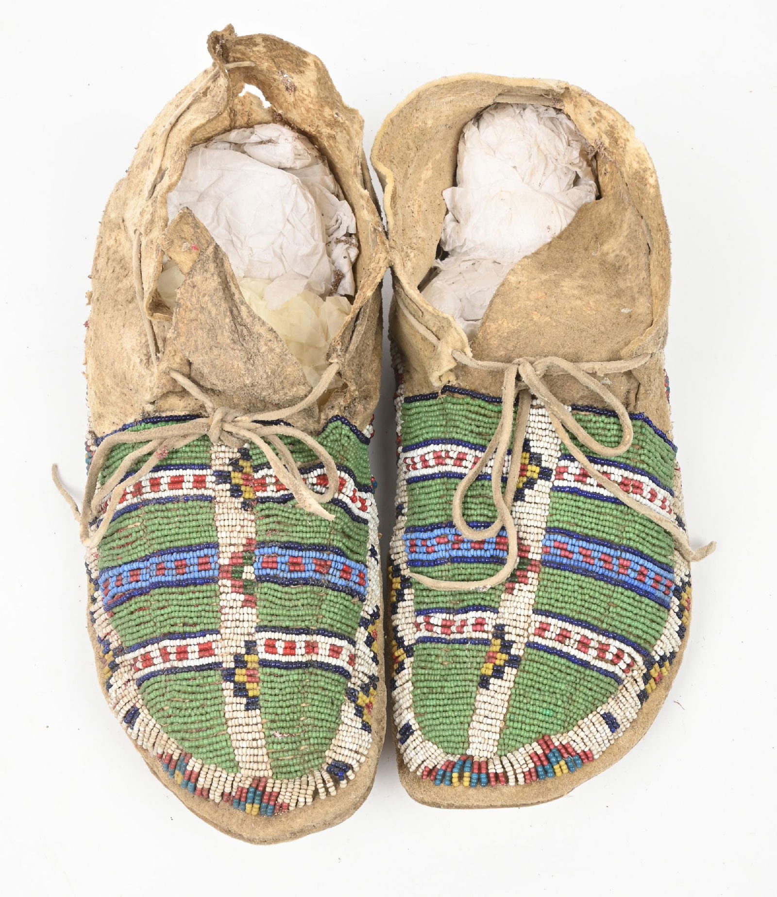 GREEN AND WHITE BEADED SIOUX MOCCASINS: Constructed of Indian tanned hide with sinew sewn striped and geometric patterns on a dusty green field. 11" Length. CONDITION: Very good. Dimensions: 11" L.