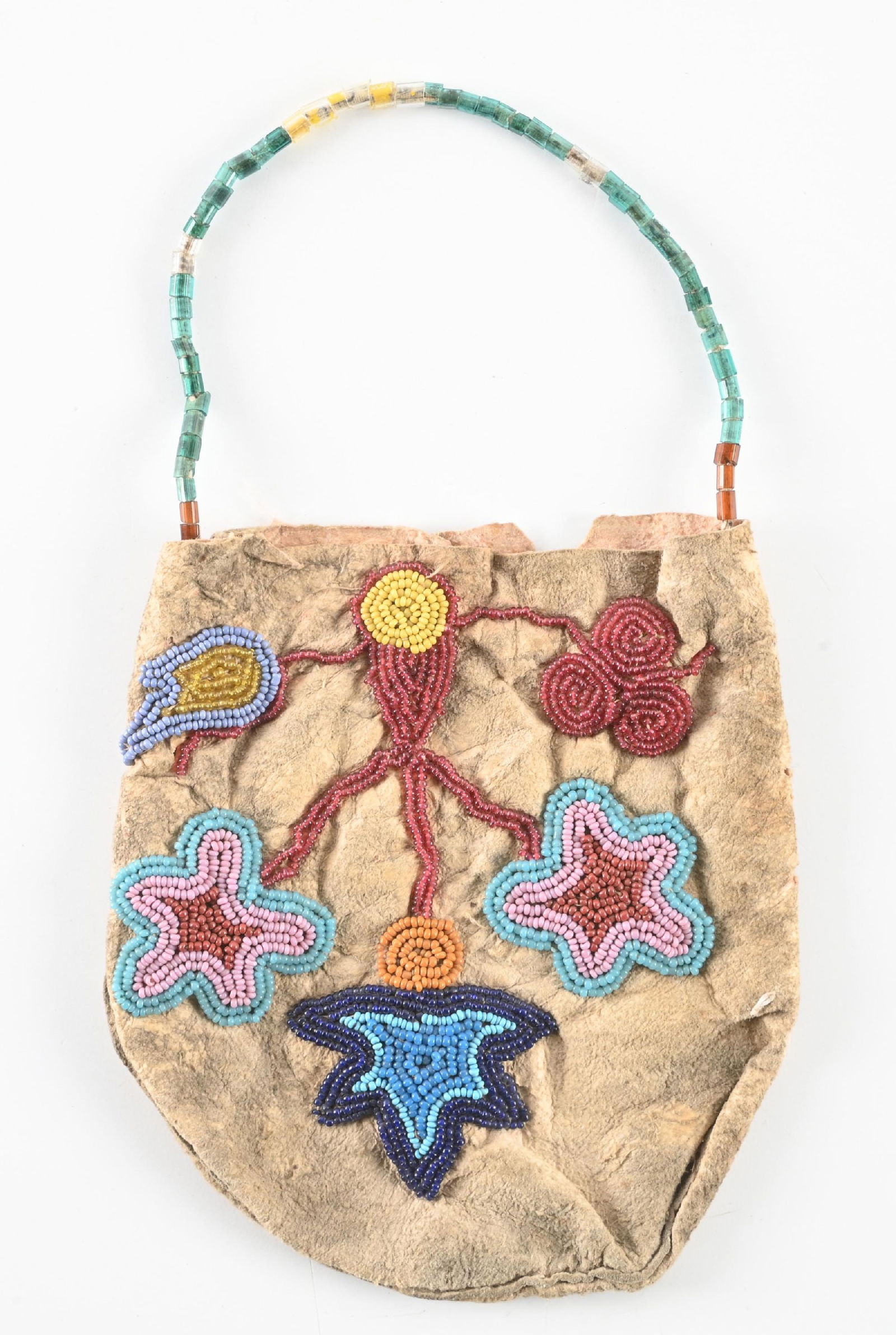 NATIVE AMERICAN BEADED BAG: Plains Cree floral beaded bag on native tanned buckskin with a beaded handle. Circa 1880s. 5" W x 5 1/2" L. CONDITION: Very good. Dimensions: 5" x 5 1/2"