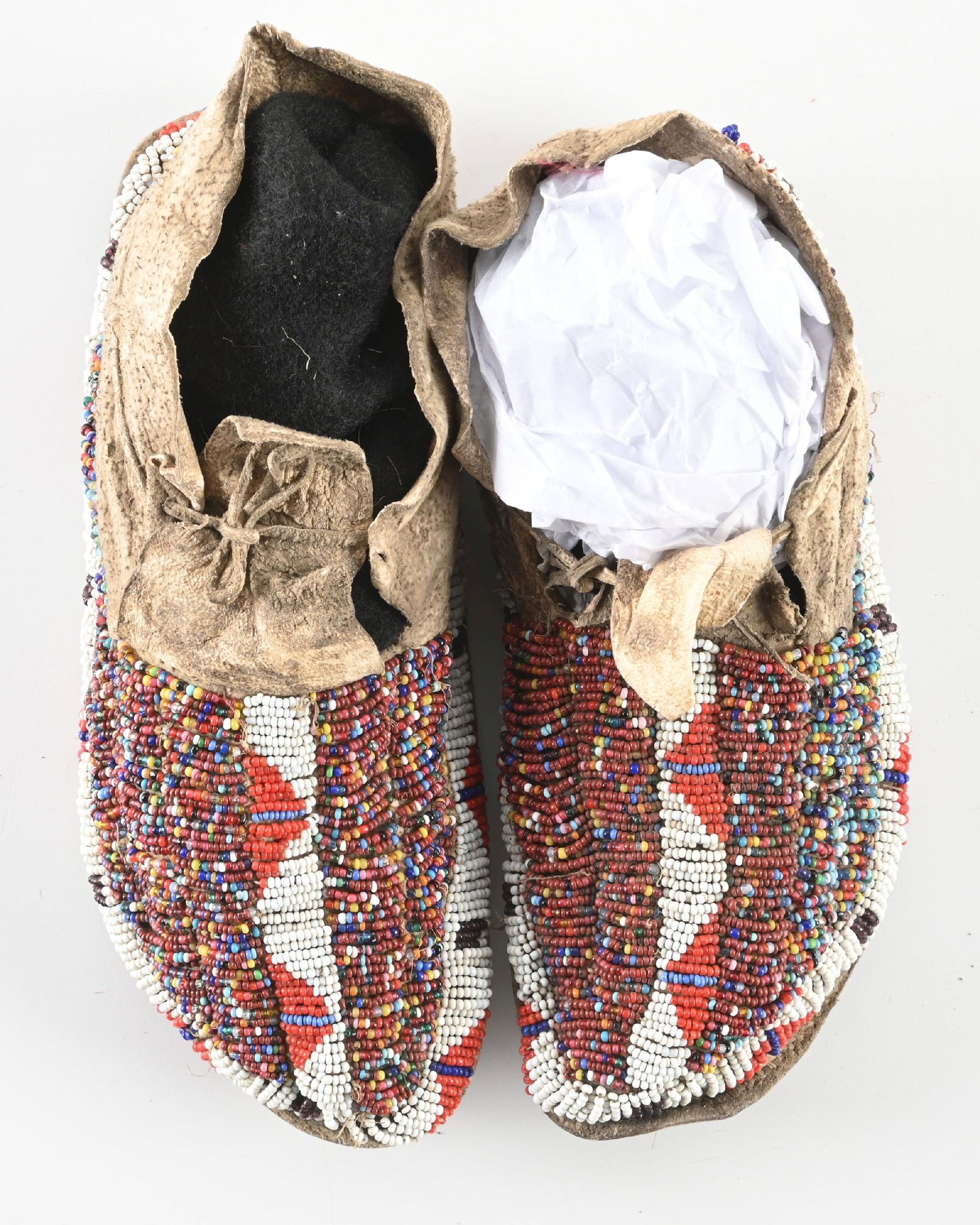 MULTI-COLORED BEADED MOCCASINS: Plains "salt and pepper" beaded moccasins. Sinew sewn, circa 1890-1910. CONDITION: Good, stiff soles. Dimensions: 8 1/2" L