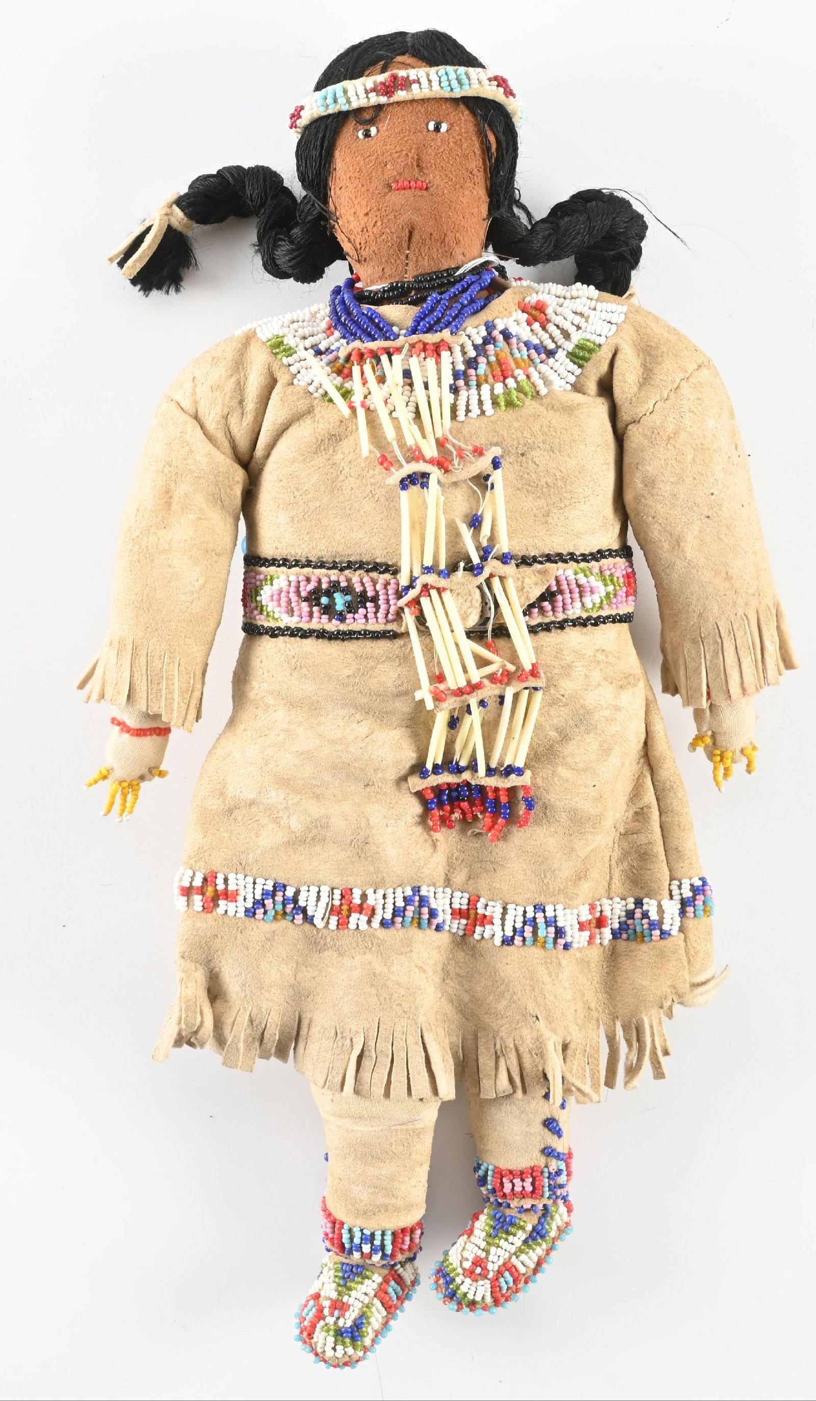 SIOUX INDIAN DOLL: Plains buckskin doll with salt and pepper style beadwork. Wool yarn hair and miniature dentalium necklace. 6" W x 13" L. CONDITION: Very good. Dimensions: 6" x 13"
