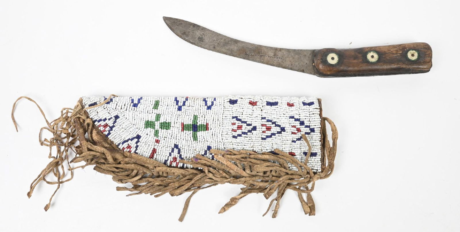 WHITE BEADED KNIFE CASE: Plains knife sheath with geometric designs and profuse edge fringe. Includes a riveted frontier skinning knife of the period. Circa 1885-1900. 8 1/4" L. CONDITION: Very good. Dimensions: 8 1/4" L