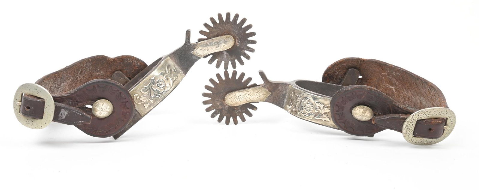 CROCKETT REPOSSEE TEXAS SPURS: A heavy 1" band with raided floral pattern on the overlay, a 2 1/4" shank and 2" rowels. Marked under the heel band, these have swing buttons and a air of basket-stamped straps.