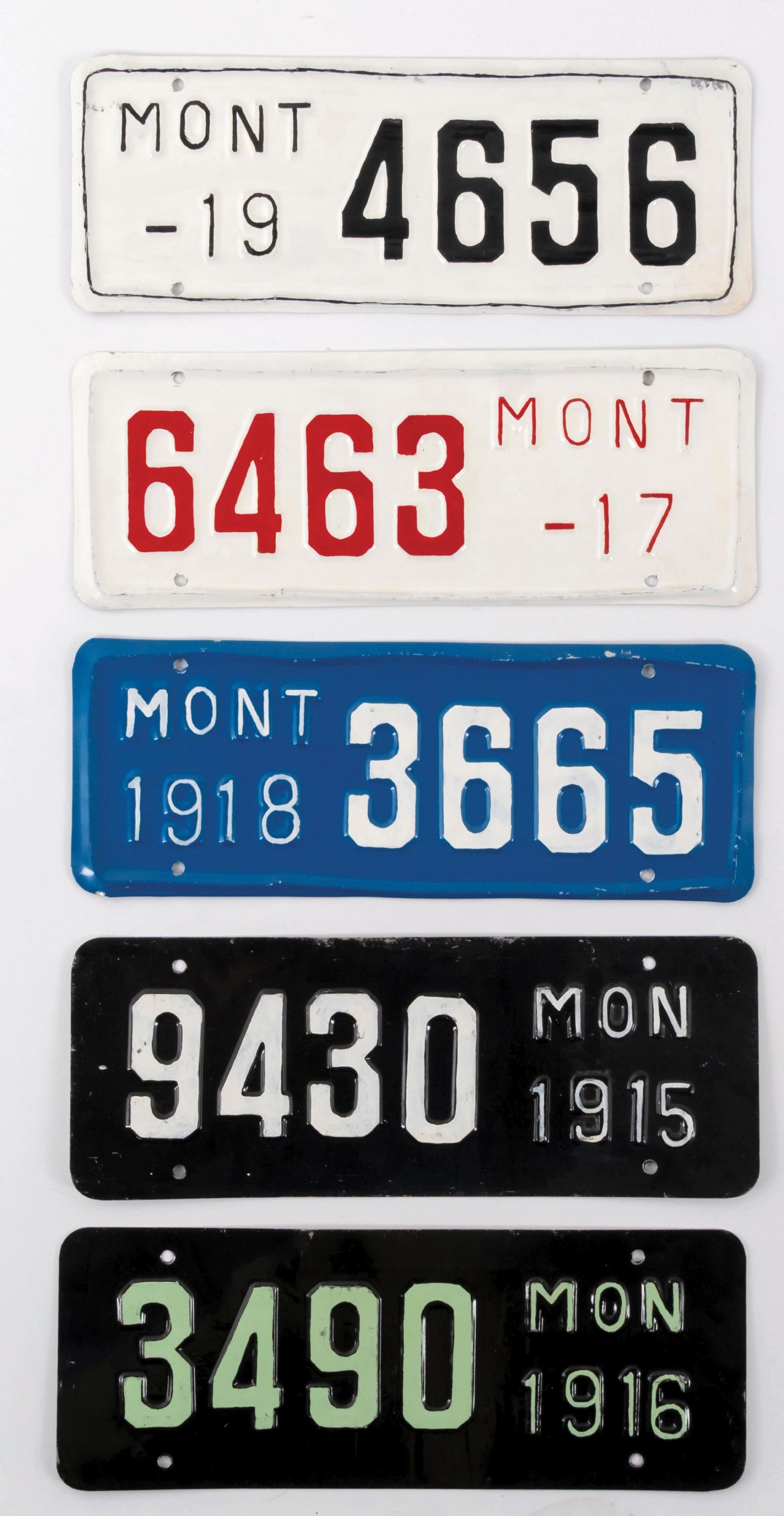 COLLECTION OF 5 MONTANA LICENSE PLATES, 1915-1919: CONDITION: Showing various colors for the years issued. There are areas of light bends, some oxidation, and areas of added paint. Condition: (7.5 - 8.0). Dimensions: Largest: 16" x 6".
