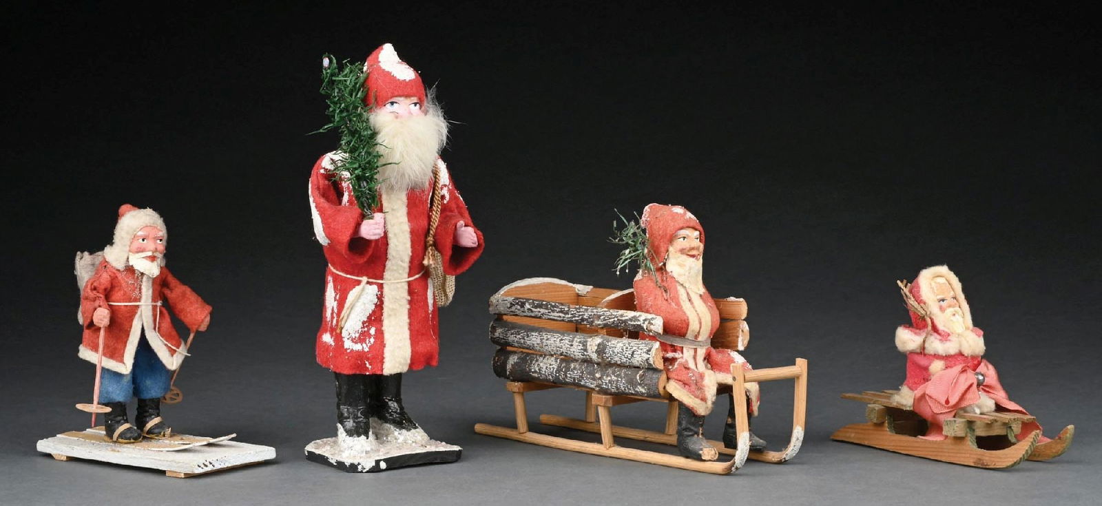 COLLECTION OF 4: FIGURAL SANTA DECORATIONS: Collection consists of Standing German Santa candy container, which is glued close, a German Santa on wooden sled, a German skiing Santa, and a German Santa on a sled. Overall the lot is in good condi