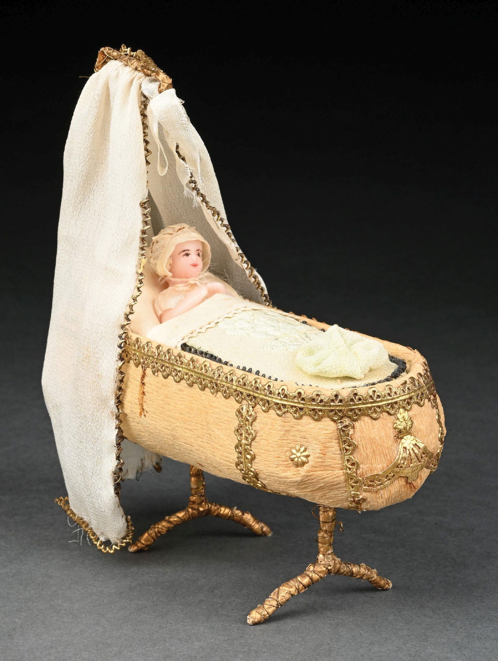 UNIQUELY DESIGNED & EXECUTED BABY IN CANOPY BED: Although we can not guarantee the exact age, this vintage creation features a wax baby sitting upright in bed with a cotton wool pillow, which slightly elevates the head, antique bonnet over the head