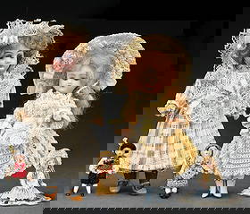 LOT OF 5: ASSORTED GERMAN BISQUE DOLLS: All with mostly original clothing. (A) The largest doll is a swivel head with closed mouth, inset blue glass eyes, painted lashes and brows, mounted to the original five-piece paper mache and composit