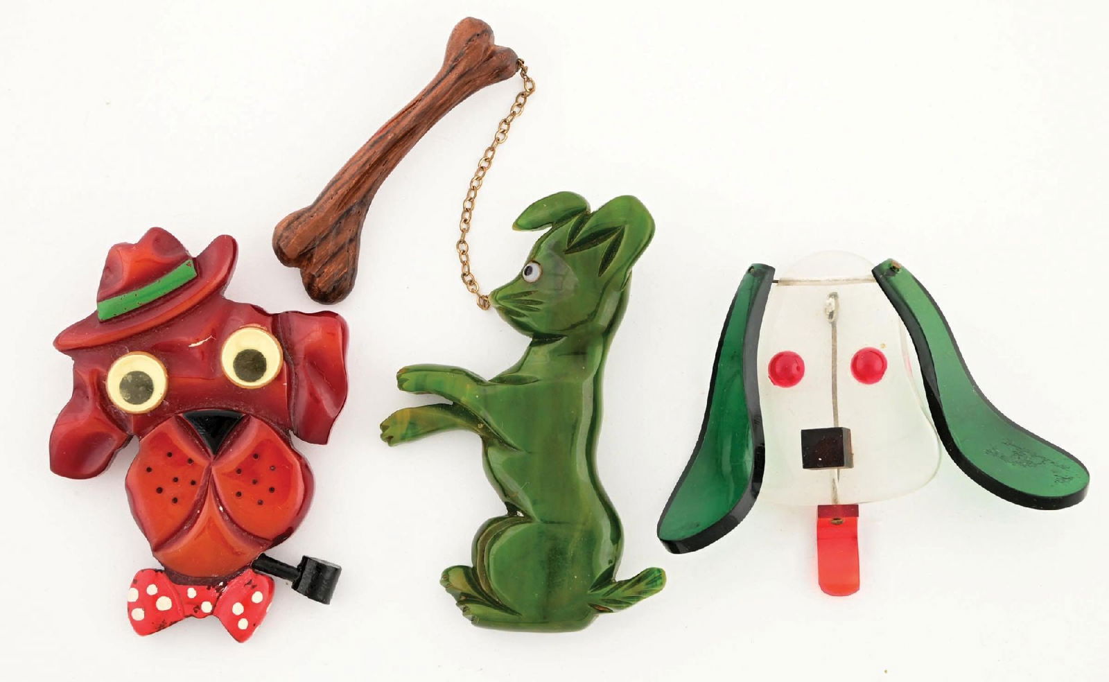 LOT OF 3: DOG BROOCHES: Lot consists of: one googly-eyed Bakelite dog brooch with hat, pipe, and polka dot bow tie, one carved Bakelite dog with carved bone charm, and one Lucite figural dog pin with movable ears and tongue.