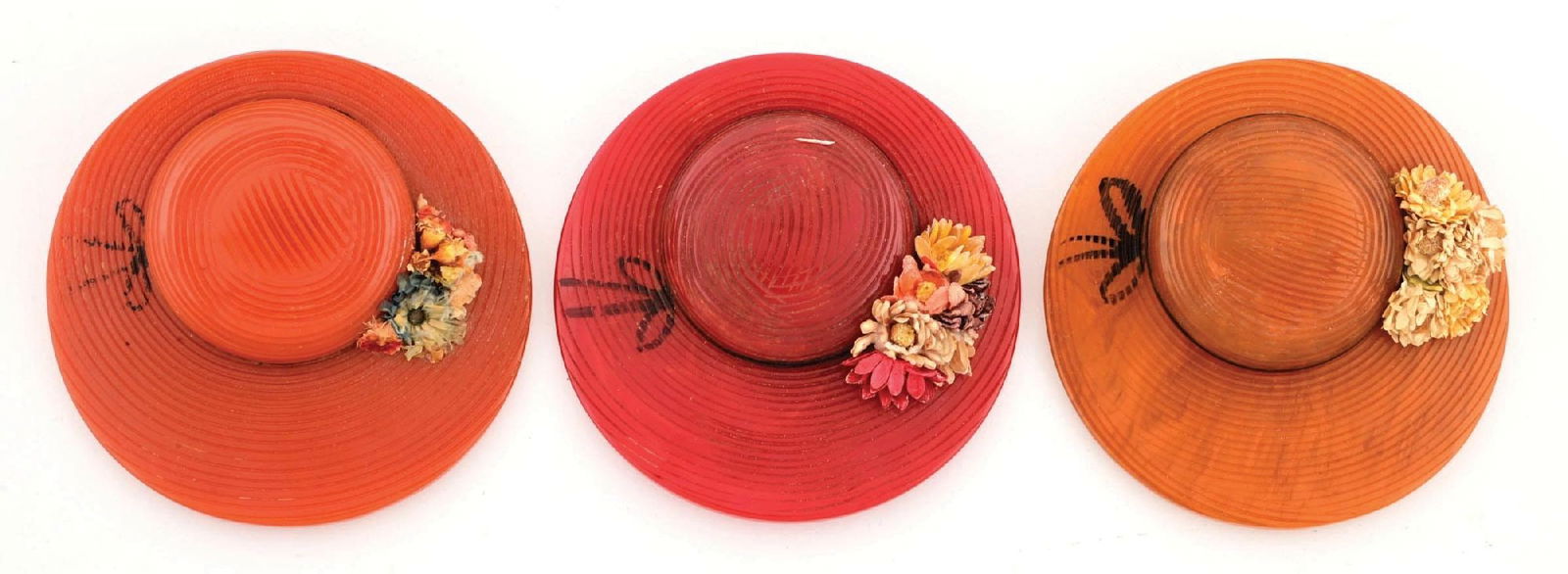 LOT OF 3: BAKELITE HAT PINS WITH VELVET FLOWERS: Lot consists of: one tan hat, one red hat, and one apricot colored hat. All hats have small velvet flower details along with painted ribbons and embossed texture on the exterior. Hats all show very li