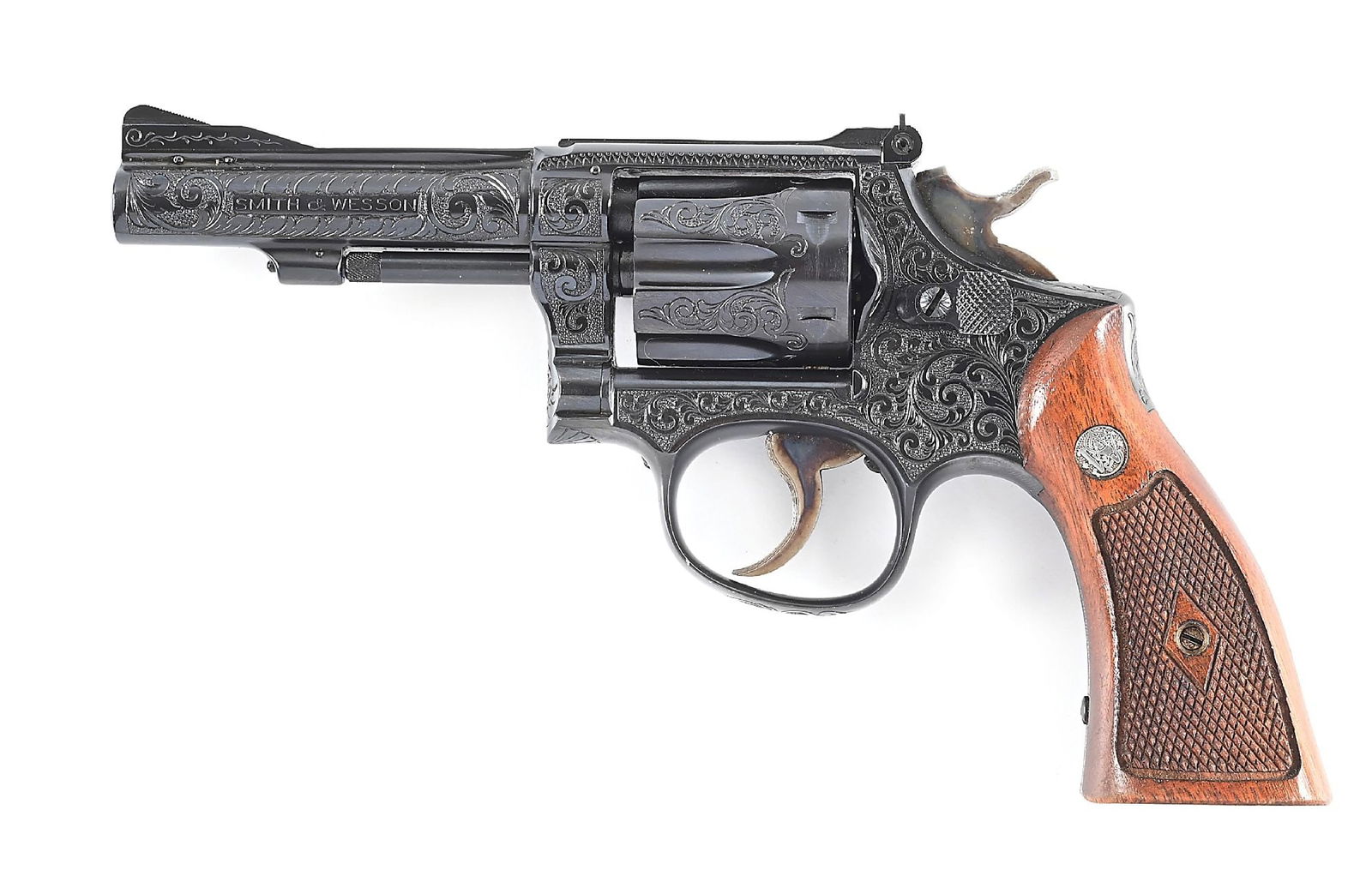 (C) ENGRAVED SMITH AND WESSON K 22 MASTERPIECE DOUBLE ACTION REVOLVER.: Shipped April 7th, 1953, to Paxton Gallagher Company, Omaha, Nebraska as a 6" blued gun with Patridge front sight and checkered walnut grips. Subsequently upgraded with nearly complete coverage of thi