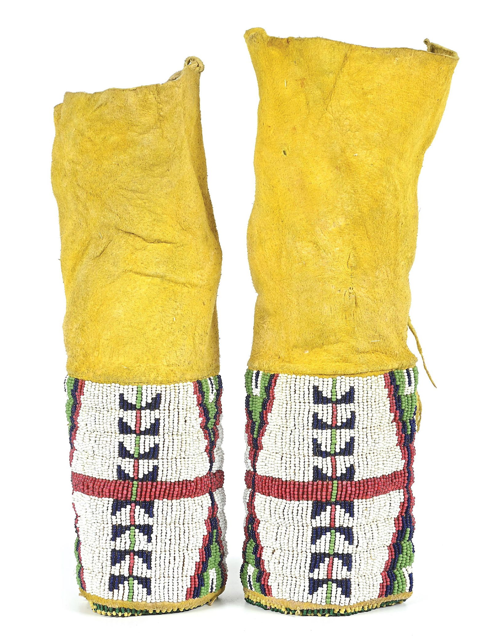 SIOUX (LAKOTA) GIRL'S LEGGINGS: With a fully beaded panel of beadwork, showcasing stepped triangles and a vertical row of repeating geometric design, surmounted by ocher-stained leather tops. Dimensions: 4" x 10" Colors: White, Whit