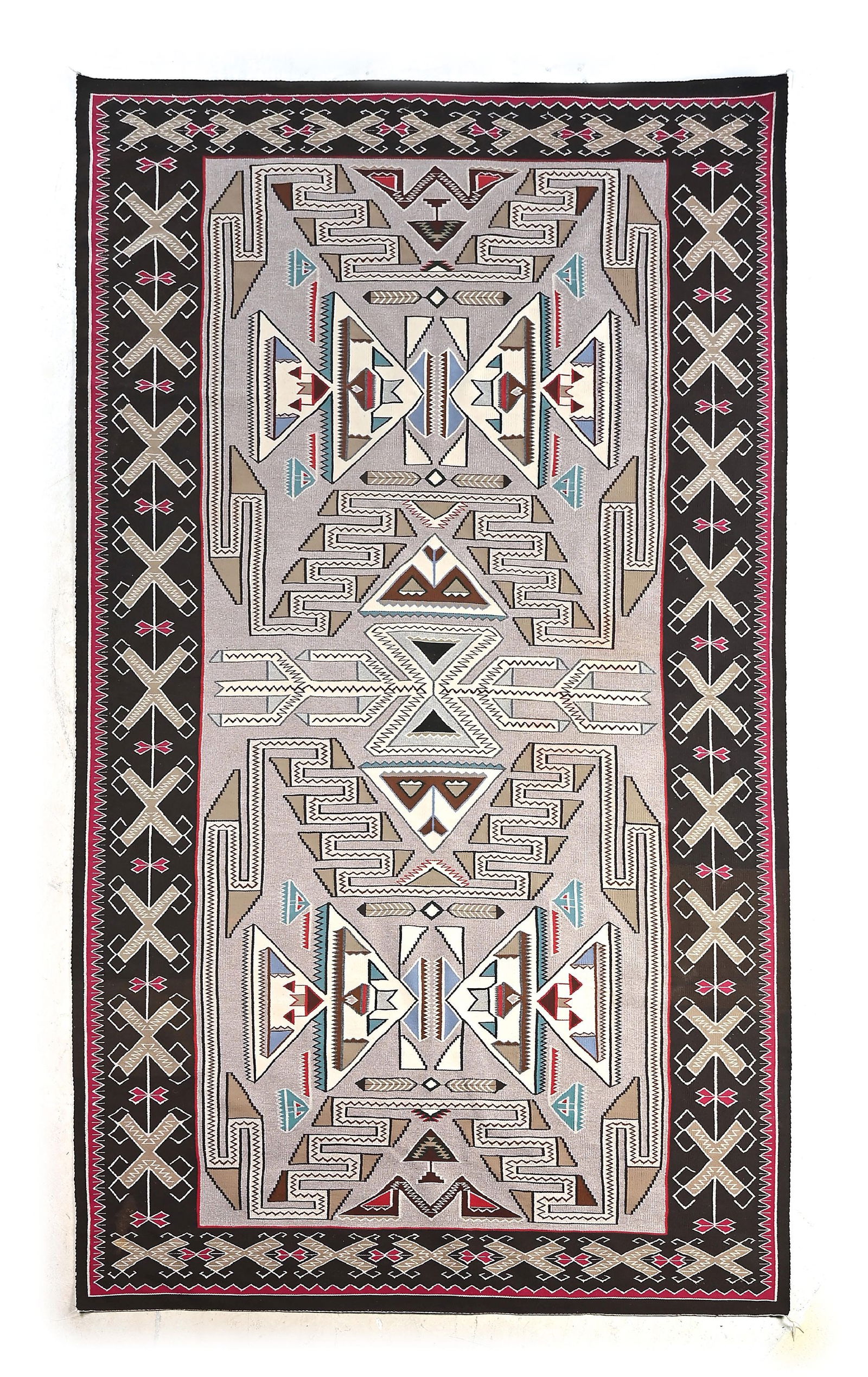 NAVAJO (DINÉ) LARGE RUG TEEC NOS POS: Contemporary. With a large central medallion flanked by reflective medallions, all encased by a border that is comprised of water bugs or "X" design. Dimensions: 84" x 132" Colors: Light Grey, Brown,