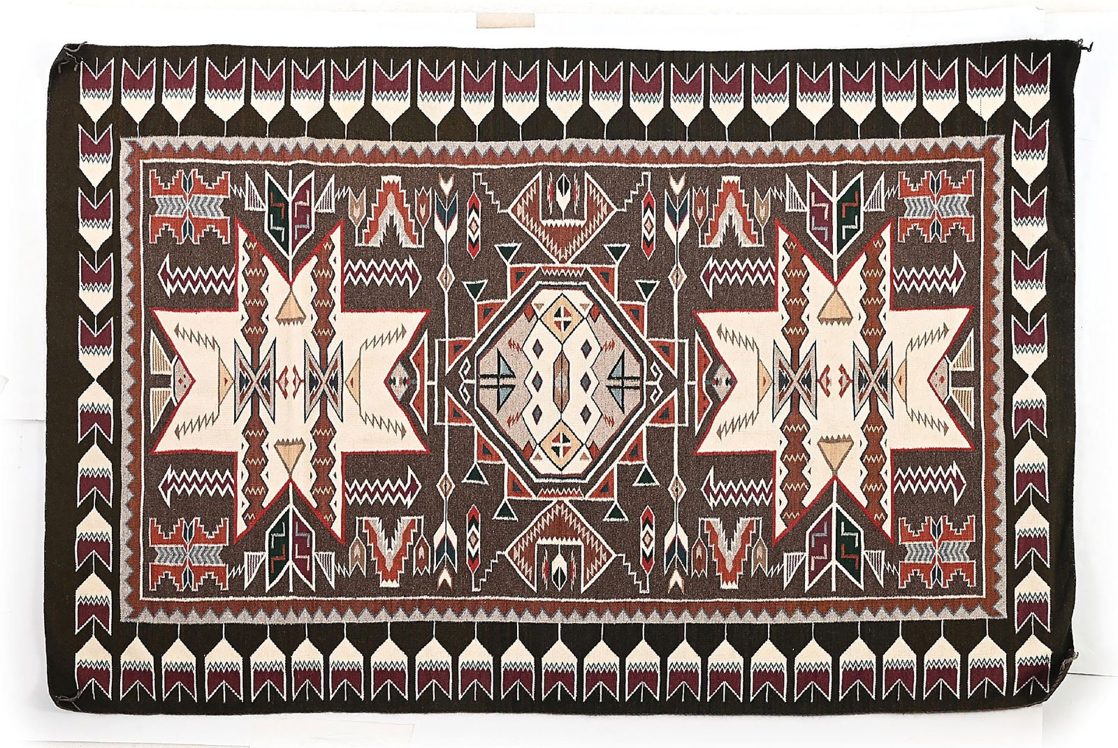 NAVAJO (DINÉ) RUG CHURRO TEEC POS: Contemporary. A central step diamond medallion flanked on each side by a large eight-point star medallion. Bordered by a feathered arrow design. Dimensions: 62" x 94" Condition: Corners are slightly c