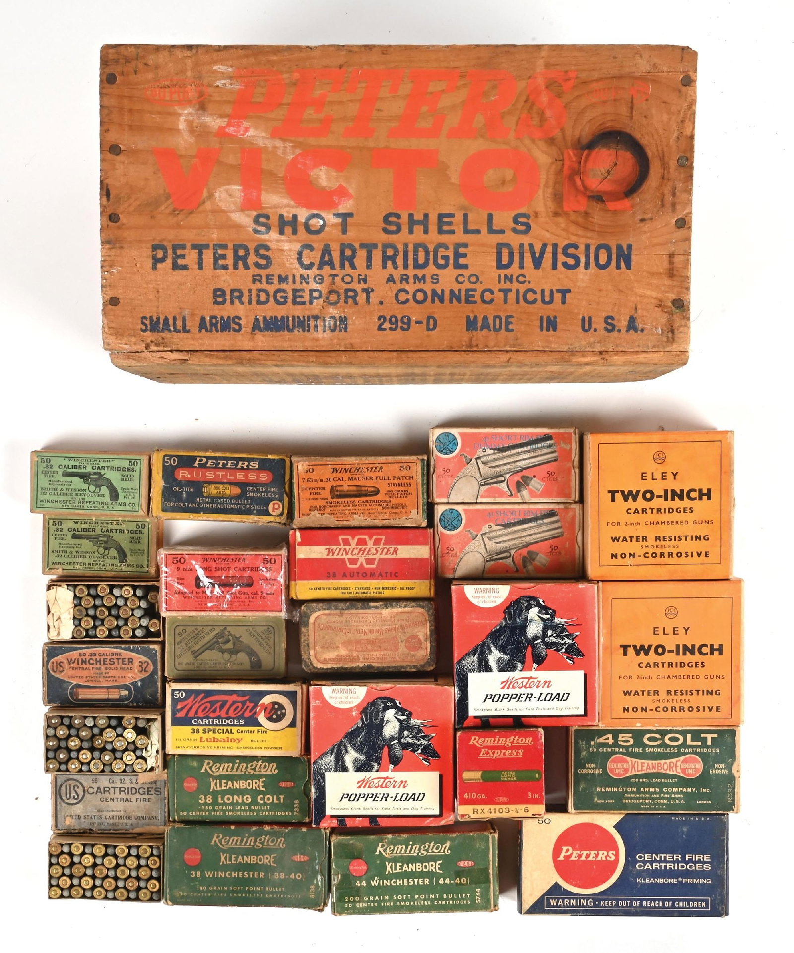 16 BOXES OF VINTAGE AMMUNITION IN WOODEN CRATE.: Full boxes include two sealed early Eley and rare 2" 12 gauge loads in the two piece boxes. Two boxes of Western 12 gauge Popper Loads. A box of 1960's Peters .45 Auto Rim. a Remington Dog Bone box of