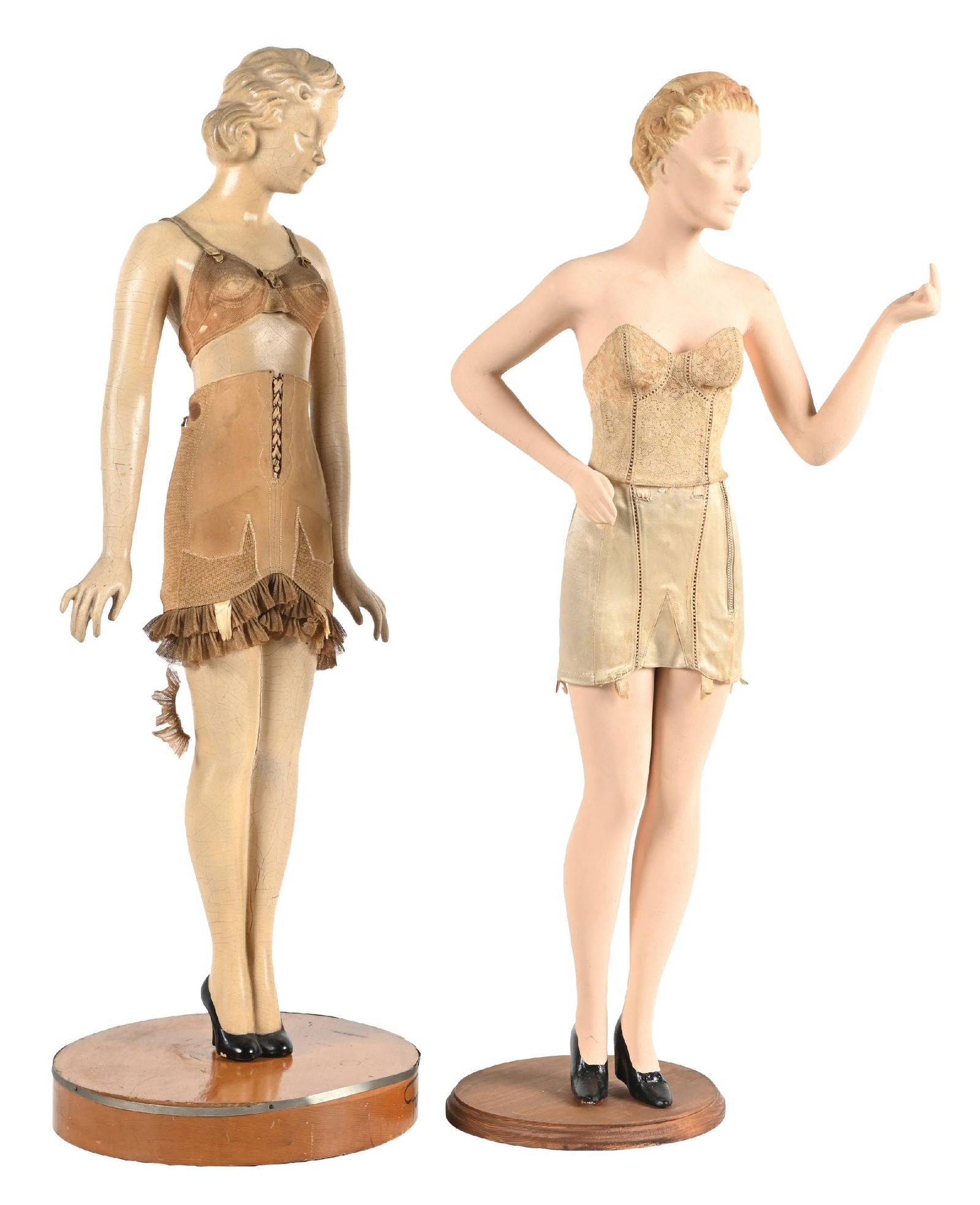 PAIR OF COUNTERTOP LINGERIE MANNEQUINS: CONDITION: (A) A composition mannequin, showing areas of foxing to the finish throughout. It has an original lingerie garment and dowel wood stand. It shows an advertisement for "Form Fit". (8.0). (B)