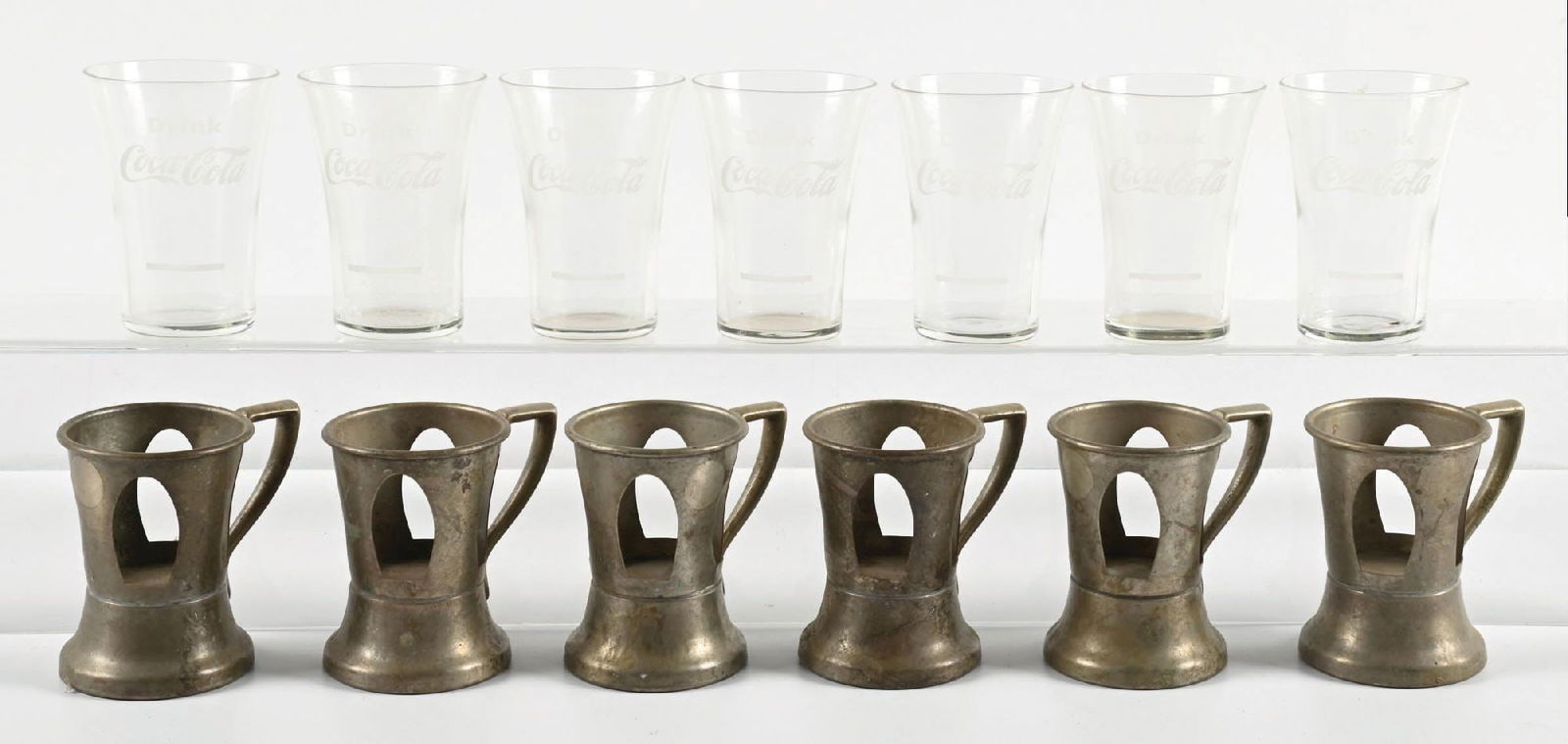 COLLECTION OF 13: COCA-COLA GLASSES W/ 6 LILLY CUP HOLDERS: CONDITION: Showing no chips to the Coca-Cola glasses, and patina to the Lilly cup holders consistent with age. Condition: (Very Good). Dimensions: Largest: 3 - 3/4" T. x 2 - 3/4" Dia.