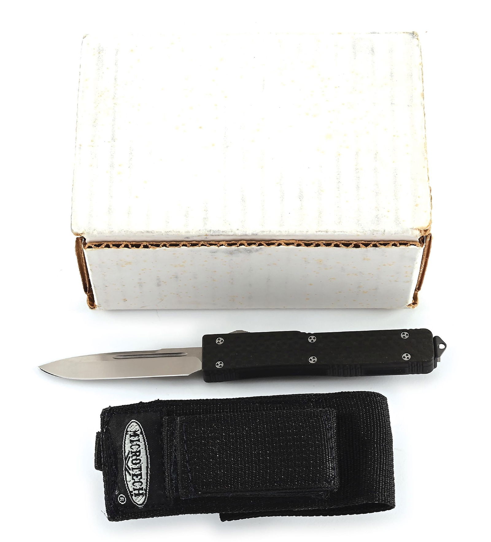 MICROTECH UTX 70 CARBON FIBER HANDLE OTF AUTOMATIC KNIFE.: Microtech UTX-70 that features a stonewash plain blade with swedge and fullers. Black aluminum frame with carbon fiber face scale. Ramped thumb slide with blasted stainless steel tip down clip marked