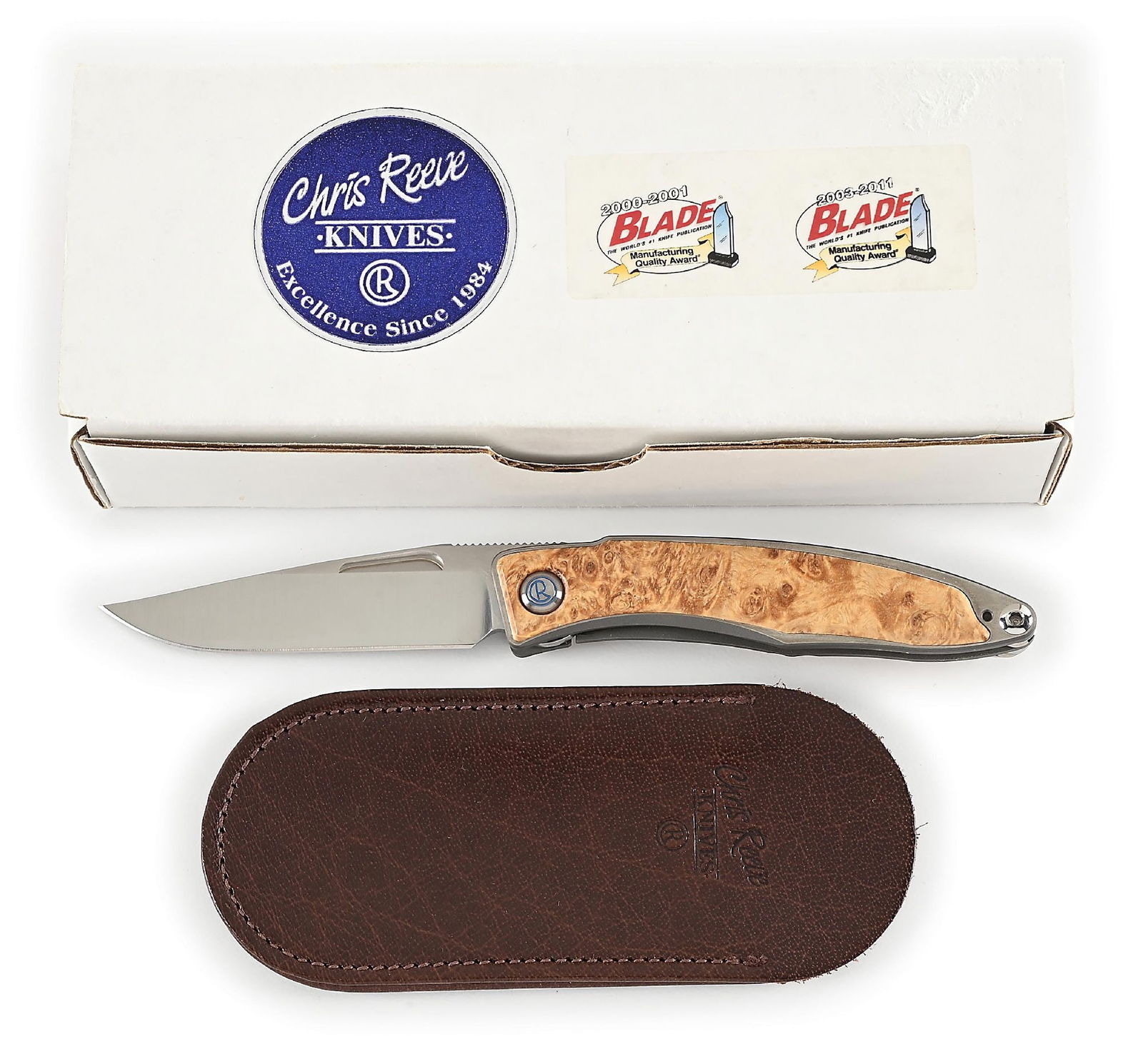CHRIS REEVE BOXED MNANDI.: Features a satin finished S35VN blade with nail nick assists and knurled thumb rest. Titanium frame with box elder burl inlays. The knife operates using a linerlock mechanism that functions properly.