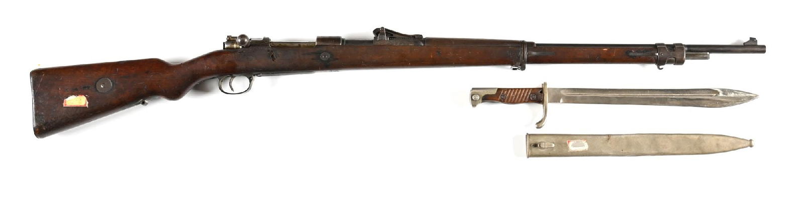 (C) AMBERG GEWEHR 98 8MM MAUSER BOLT ACTION RIFLE WITH BAYONET.: Manufactured in 1914. Blued barrel with ramped barleycorn front sight and rollercoaster rear. Standard walnut stock with steel mounts. A very old sticker attached to the stock reads "ARGRONNE FOR" pos
