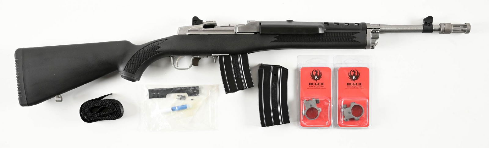 (M) RUGER RANCH SEMI-AUTOMATIC RIFLE IN 5.56 NATO WITH BOX.: Brushed stainless finish with checkered black nylon stock. All standard features, and comes in its matching numbers box, paperwork, and set of scope rings. CONDITION: Shows in near new condition with