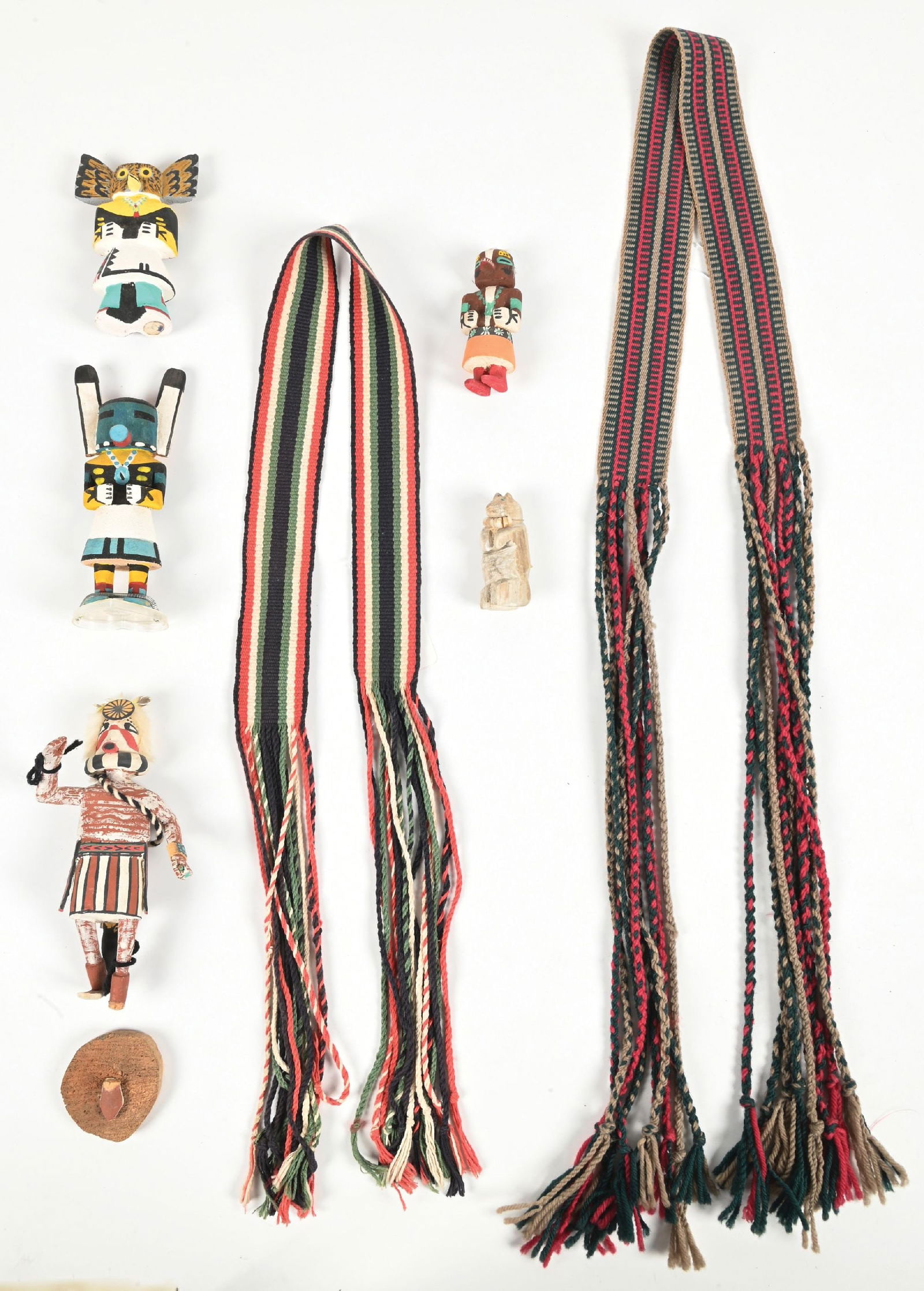LOT OF 7: KACHINAS & SASHES: Includes 3 Route 66 Kachinas, 1 later Kachina with broken foot, Zuni antler Fetish, and 2 Pueblo sashes. Provenance: Estate of N. Harman. Dimensions: Largest: 2 - 1/2" x 7".