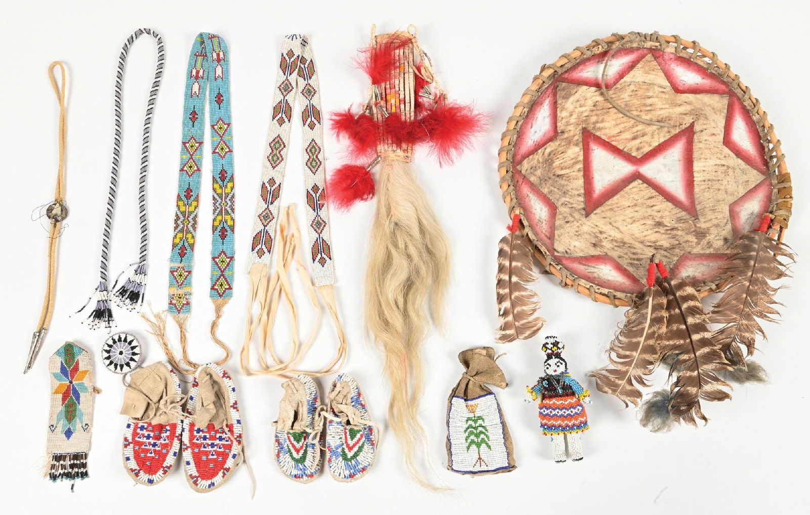 LARGE LOT OF NATIVE AMERICAN BEADWORK AND ARTIFACTS: Including two pairs of child moccasins, Zuni doll, quill dance drop, and decorative shield. Provenance: Estate of N. Harman. Dimensions: Largest: 14 - 1/4" Dia.