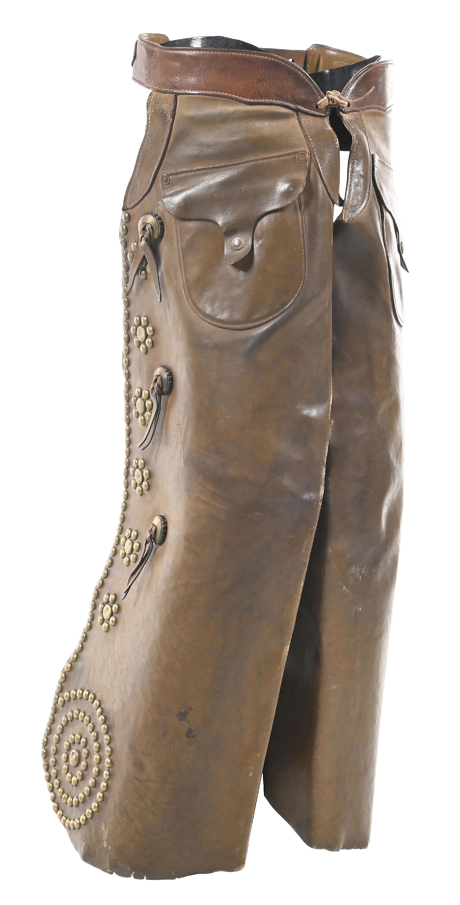 H. H. HEISER STUDDED CHAPS: A brown pair of batwing chaps with brass studs along the edge, culminating down at the corner in a target pattern. There are size circle-dot stud patterns along each leg along with three slotted conch