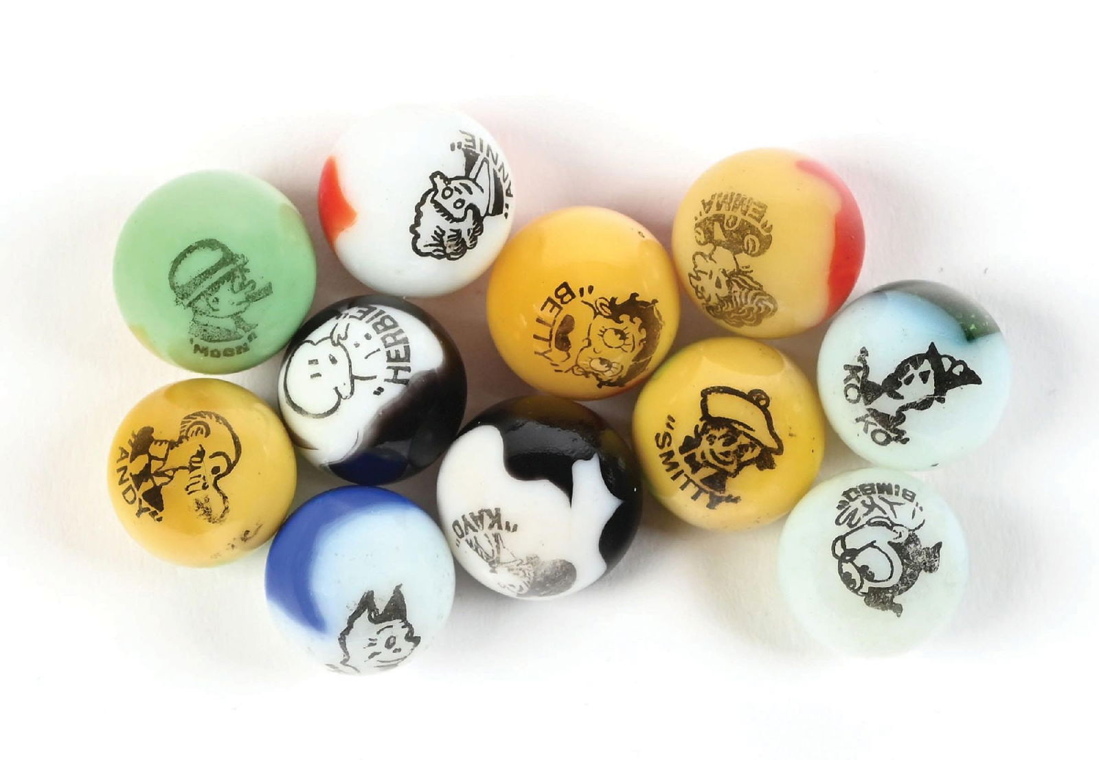 LOT OF 11: COMIC MARBLES: 21/32" - 11/16" diam. Includes a Moon on green base, Kayo, Annie, Herbie, Smitty, Sandy, Emma, Ko Ko, Andy, Bimbo, and Betty on yellow base. Condition: (9.3). Dimensions: Each: 5/8" Dia.
