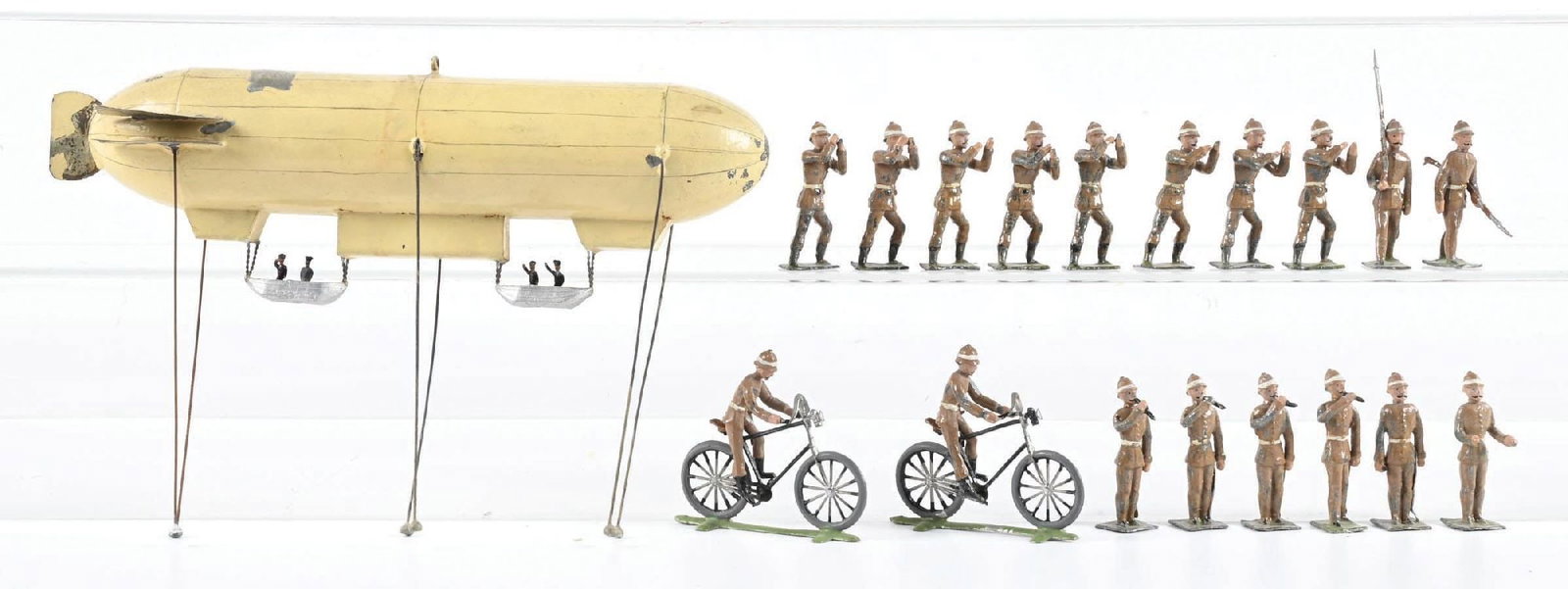 HEYDE DIRIGIBLE W/ GROUND CREW ASSORTMENT: Includes 8 ground crew, 2 bicyclists, 2 armed sentries, an open-handed troop, and 5 fifers. Zeppelin is complete with original paint. Average, played-with condition. 19 pieces total. Condition: Dimens