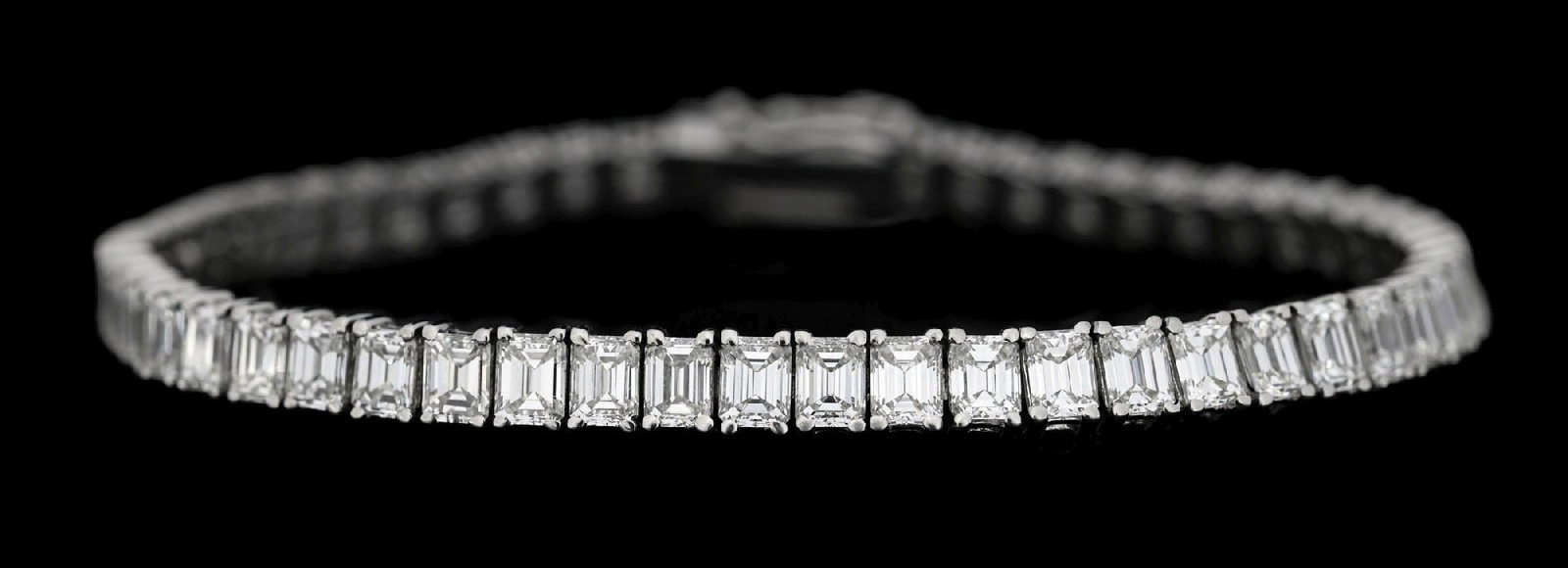 PLATINUM 12CT TW DIAMOND BRACELET: Ladies' platinum prong-set diamond line bracelet consisting of 58 emerald cut natural diamonds with a total weight of 11.83cts, graded H, VS. Gross weight is 22.0 grams. Length measures 7-1/4". Width 