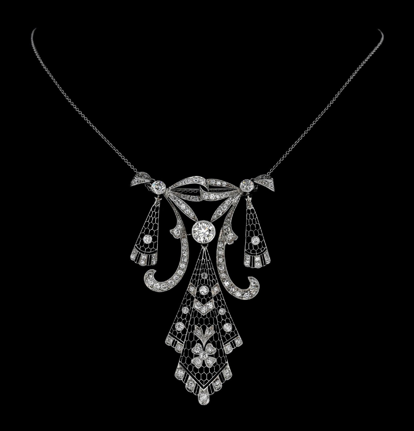 PLATINUM EDWARDIAN 4CT TW DIAMOND NECKLACE: Ladies' stunning Edwardian handmade platinum and diamond pendant/brooch with fine a 14k white gold link chain, consisting of one large central bezel-set European cut natural diamond measuring approxim