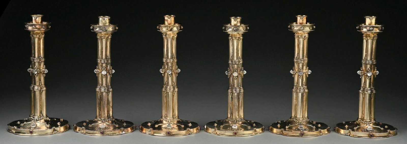 A SET OF SIX ENGLISH SILVER-GILT CANDLESTICKS: London 1988 by Michael Bolton, each with a four-part stem on a raised gently dished base with a hammer-finish, and set with cabochon stones. Marked on bases. Height: 10-1/2". Total weight: 143.5 ozt. 