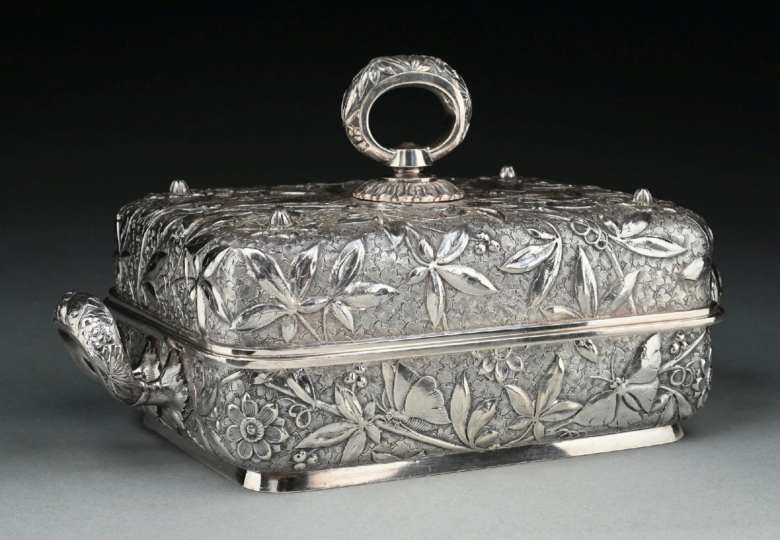 AN AMERICAN STERLING COVERED VEGETABLE DISH: Dominick & Haff, 1881, retailed by Theodore Starr, the oblong top and bottom chased with flower heads, floral sprays and butterflies. Length: 12-1/4". Weight: 55.6 ozt. Condition: Dimensions: