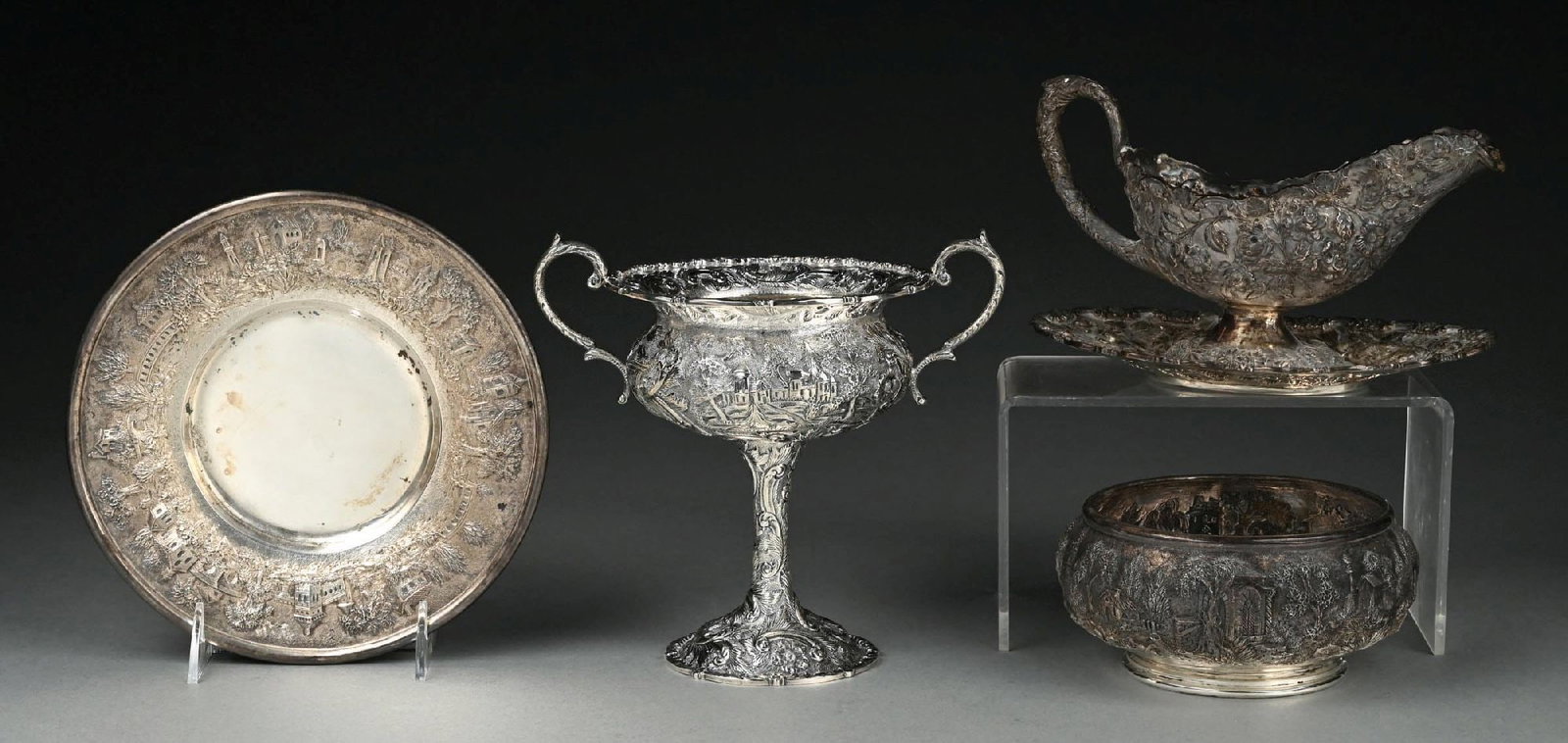 A GROUP OF AMERICAN STERLING REPOUSSE ARTICLES: Including an S Kirk gravy boat on stand, chased with rose sprays; a circular bowl and under plate, also Kirk, the sides of both chased with architectural scenes; and a tall compote, Loring Andrews,
