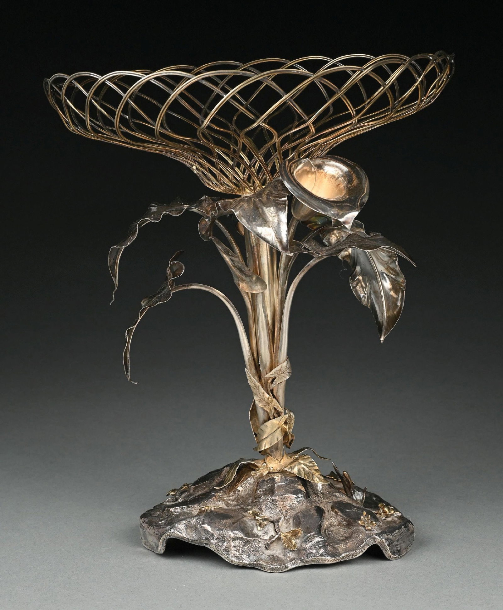 A GORHAM STERLING CENTERPIECE: 1870. Formed as a spray of lilies on a terrain base all supporting a wirework basket. Height: 12-1/4". Weight: 30.5 ozt. Condition: Dimensions:
