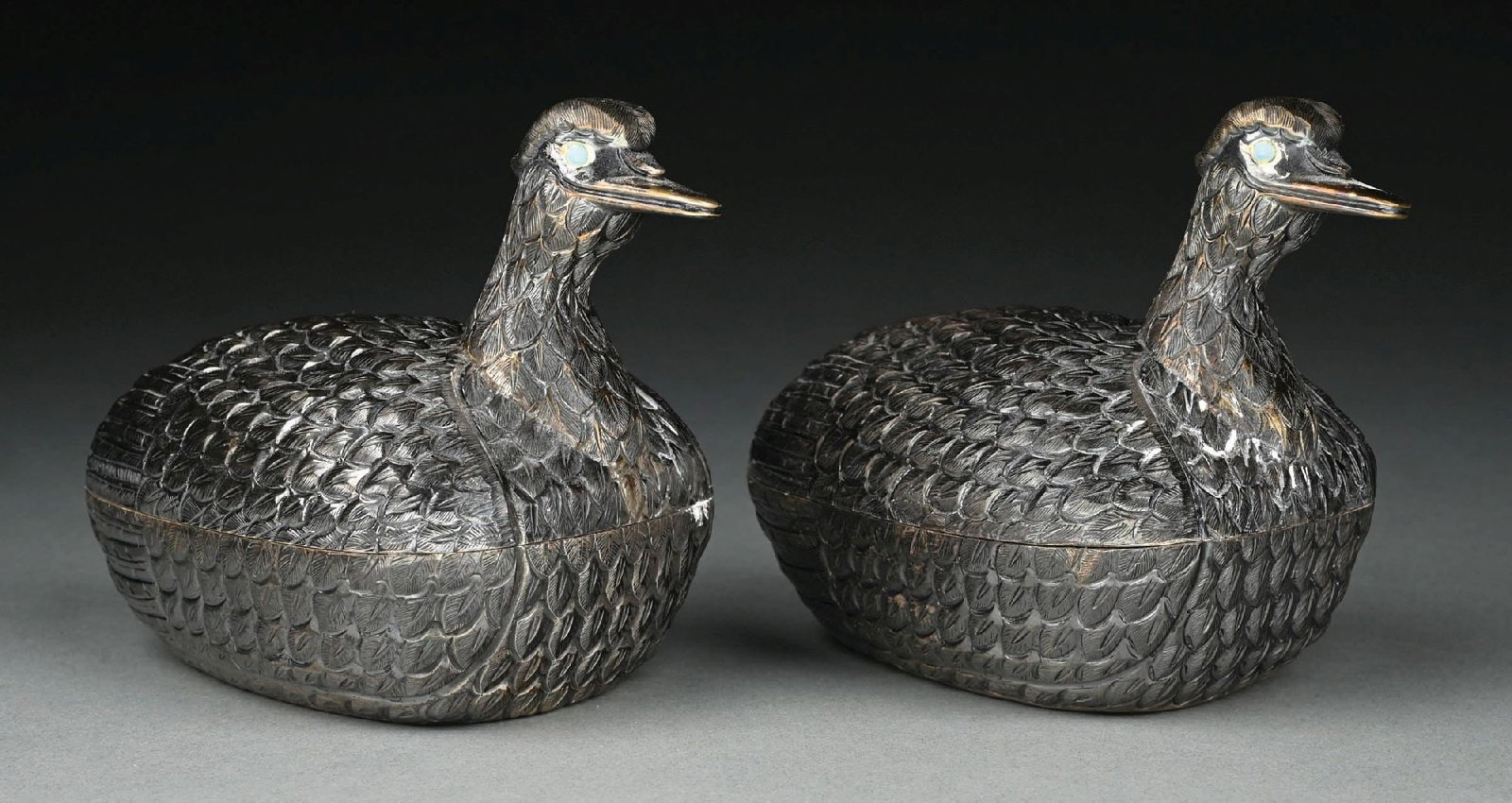 A PAIR OF MEXICAN STERLING BOXES: Tane, modelled as ducks, each with an ovoid body chased with feathers, the head set with green glass eyes. Length: 6-3/4". Total weight: 34.5 ozt. Condition: Dimensions: