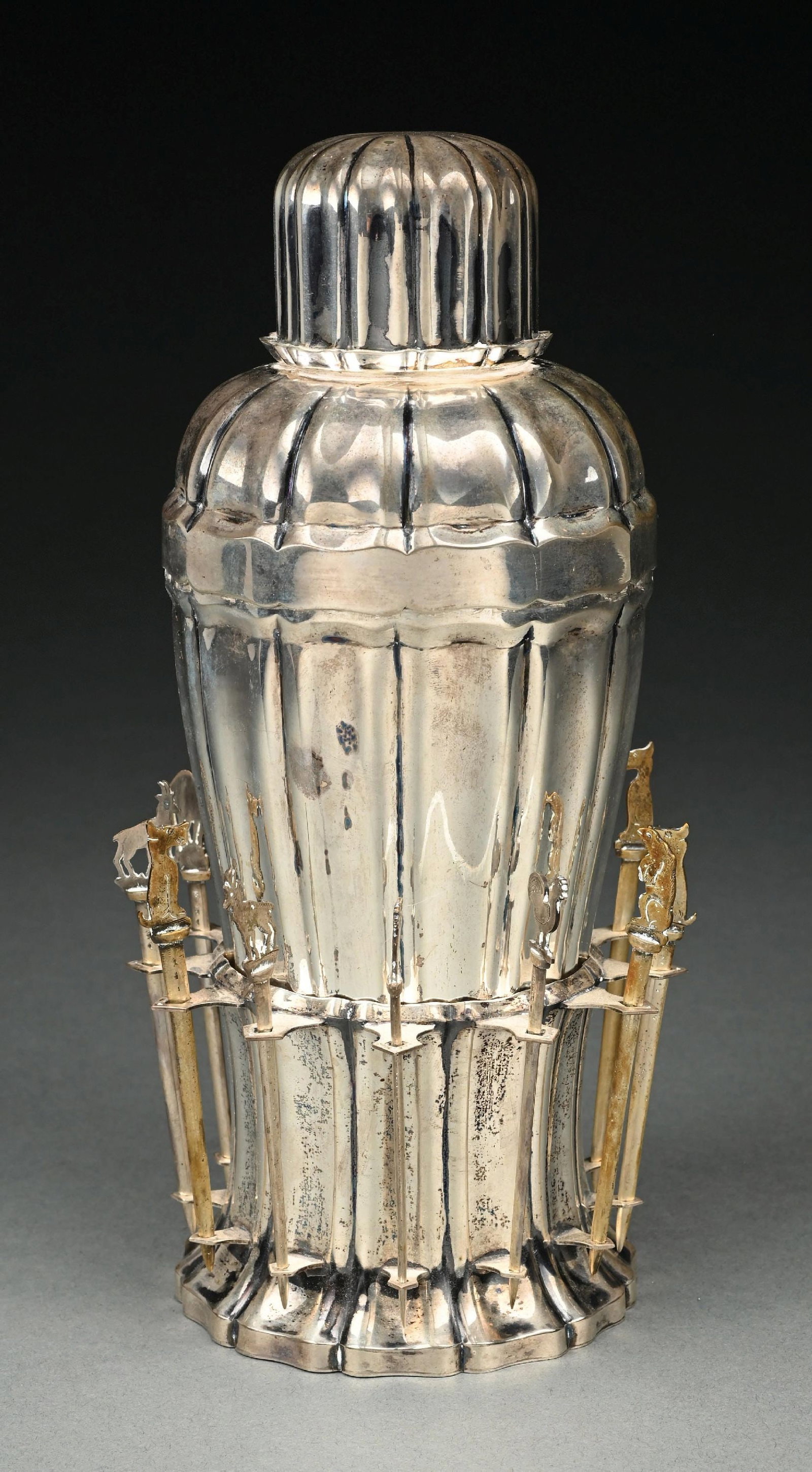 A CONTINENTAL SILVER COCKTAIL SHAKER AND BASE: The shaker with ribbed sides and lid, the base similar and with cocktail sticks around the perimeter (some not silver). .800 standard. Height: 10". Weight of silver: 27.1 ozt. Condition: Dimensions: