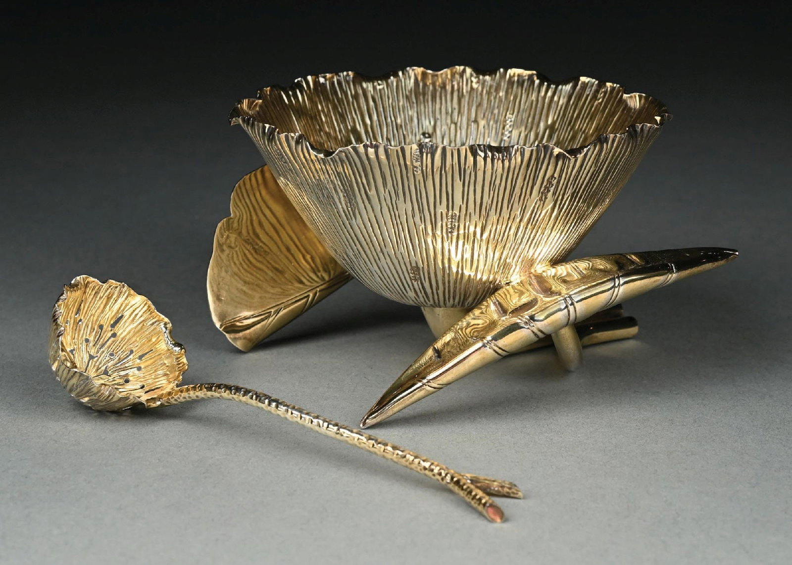 AN ENGLISH SILVER GILT SUGAR BOWL AND LADLE: Hukin and Heath London 1891, chased in the form of an open lily on a stem and leaf base, the pierced ladle with a similar bowl. Height: 3". Total weight: 8.8 ozt. Condition: Dimensions: