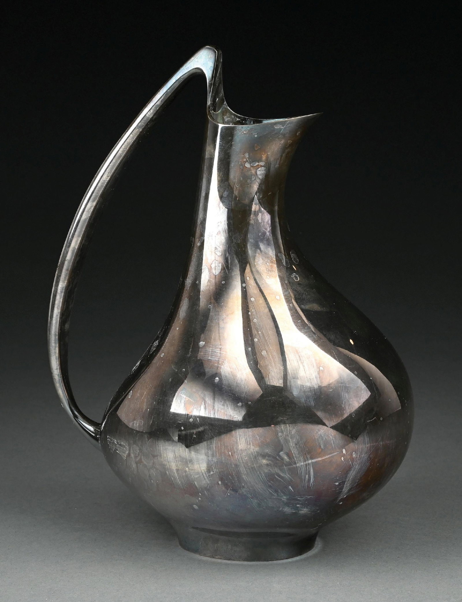 A JENSEN STERLING WATER PITCHER: The ‘pregnant duck’, model #992, with a plain shaped body tapering to a narrow neck. Height: 11-1/2". Weight: 42.5 ozt. Condition: Dimensions:
