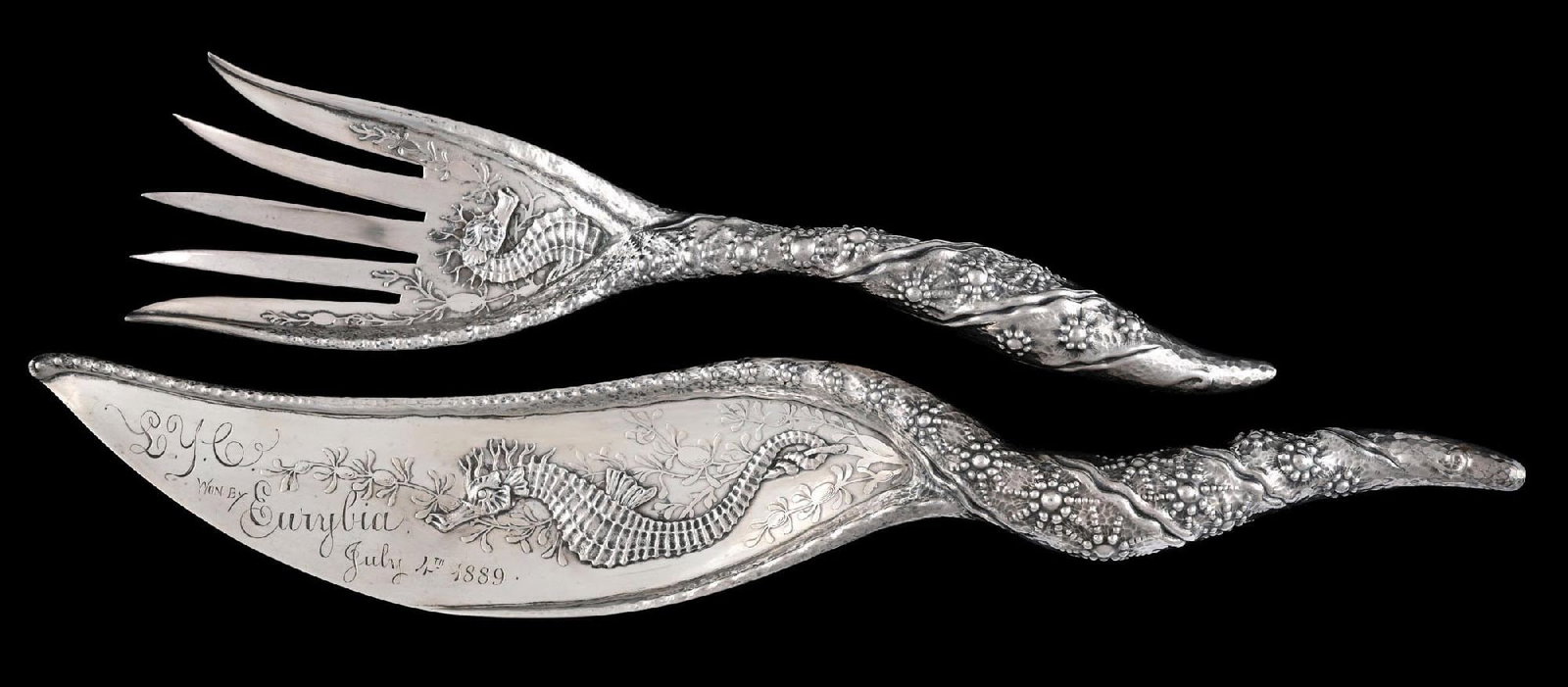 A WHITING STERLING FISH SET: C. 1889. The fork and knife cast and chased with a sea horse at the tine and blade ends and with a shaped handle with a hammer finish. Inscription on blade of knife. Length of knife: 14-1/4". Total we
