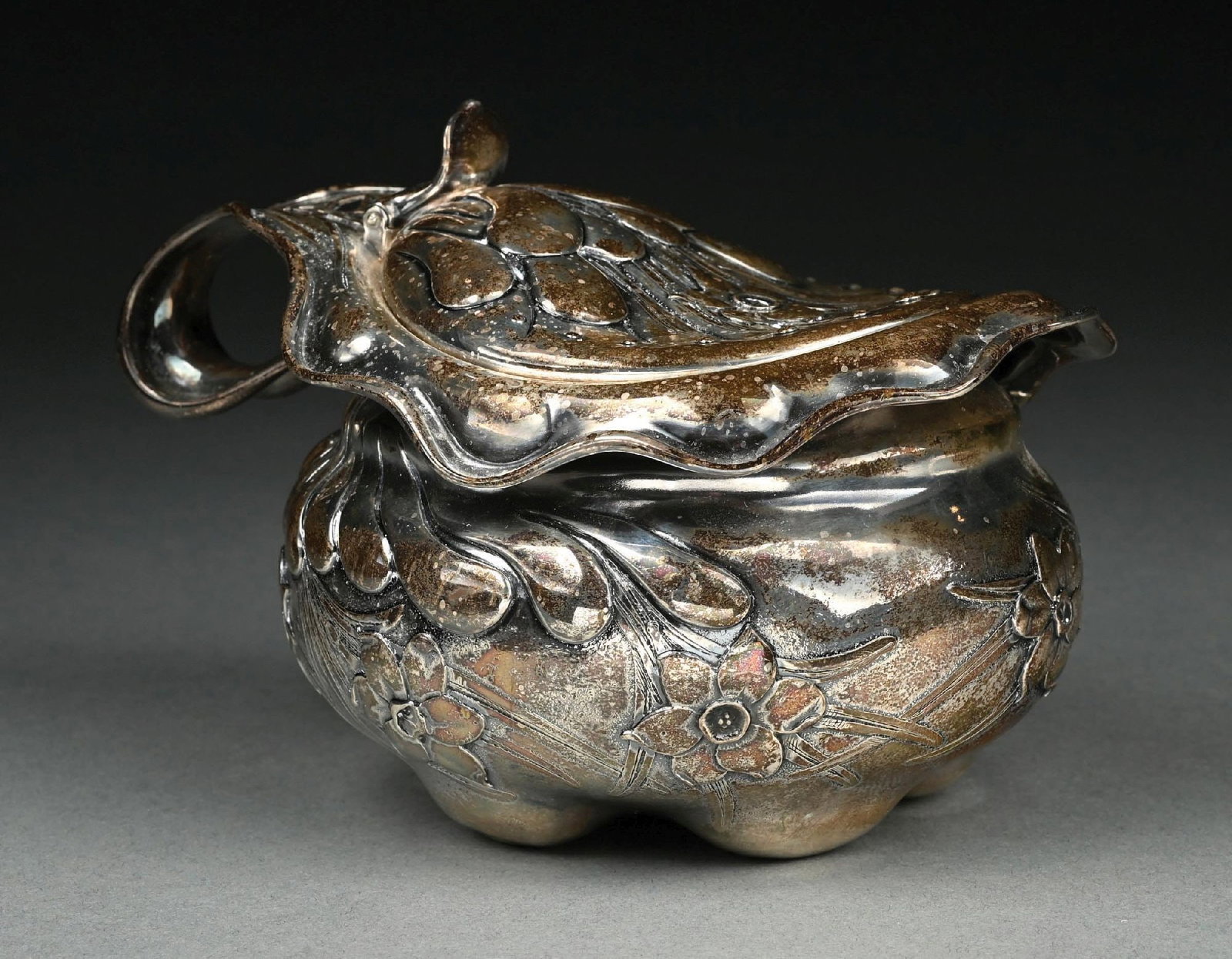 A WHITING STERLING COVERED SHORT JUG OR PITCHER: With a squat slightly oblong body and hinged lid chased with lobes and floral sprays, the handle continuing from the rim. Length: 7". Weight: 17.5. Condition: Dimensions: