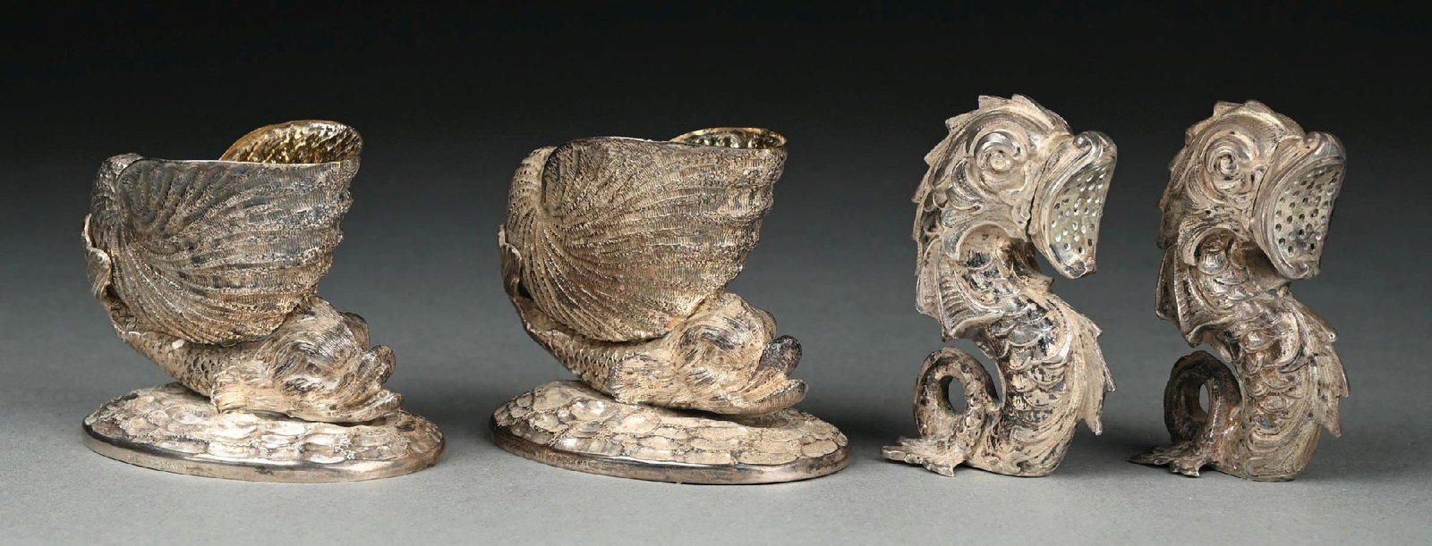 A PAIR OF AMERICAN SILVER NAUTILUS FORM SALTS: Ball Black & Co., New York, each supported on sea monster on an oval wave base; together with a pair of Continental silver salt and pepper casters, German .800 standard, in the form of upright sea mon