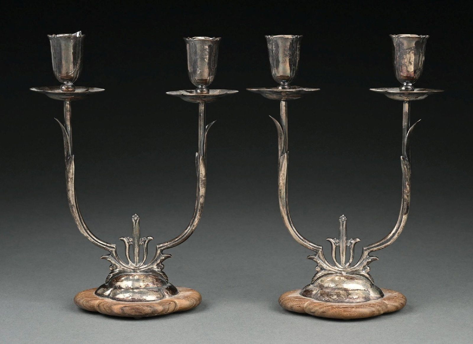 A PAIR OF AMERICAN DANISH STYLE CANDELABRA: Cellini Workshops, each with two tall arms holding lobed sockets and on a low domed base screwed to a wood platform. Height: 9". Condition: Dimensions: