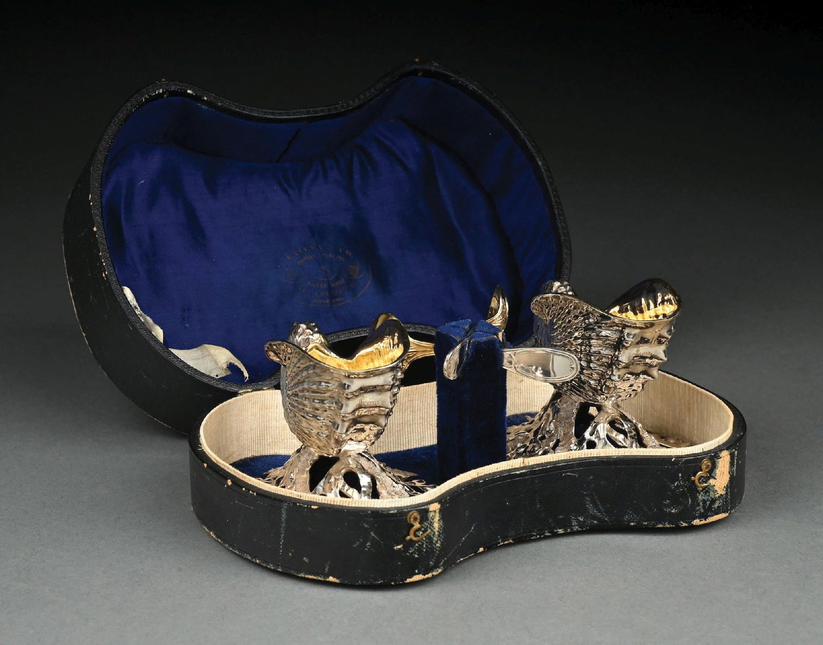A PAIR OF AMERICAN SILVER NAUTILUS FORM SALTS AND A PAIR OF SPOONS: The salts with shells on seaweed bases, the interiors gilt; the salts unmarked. In a conforming leather covered box with Bailey & Co. logo stamped in gold. Height: 2-7/8". Total weight: 11.1 ozt. Cond