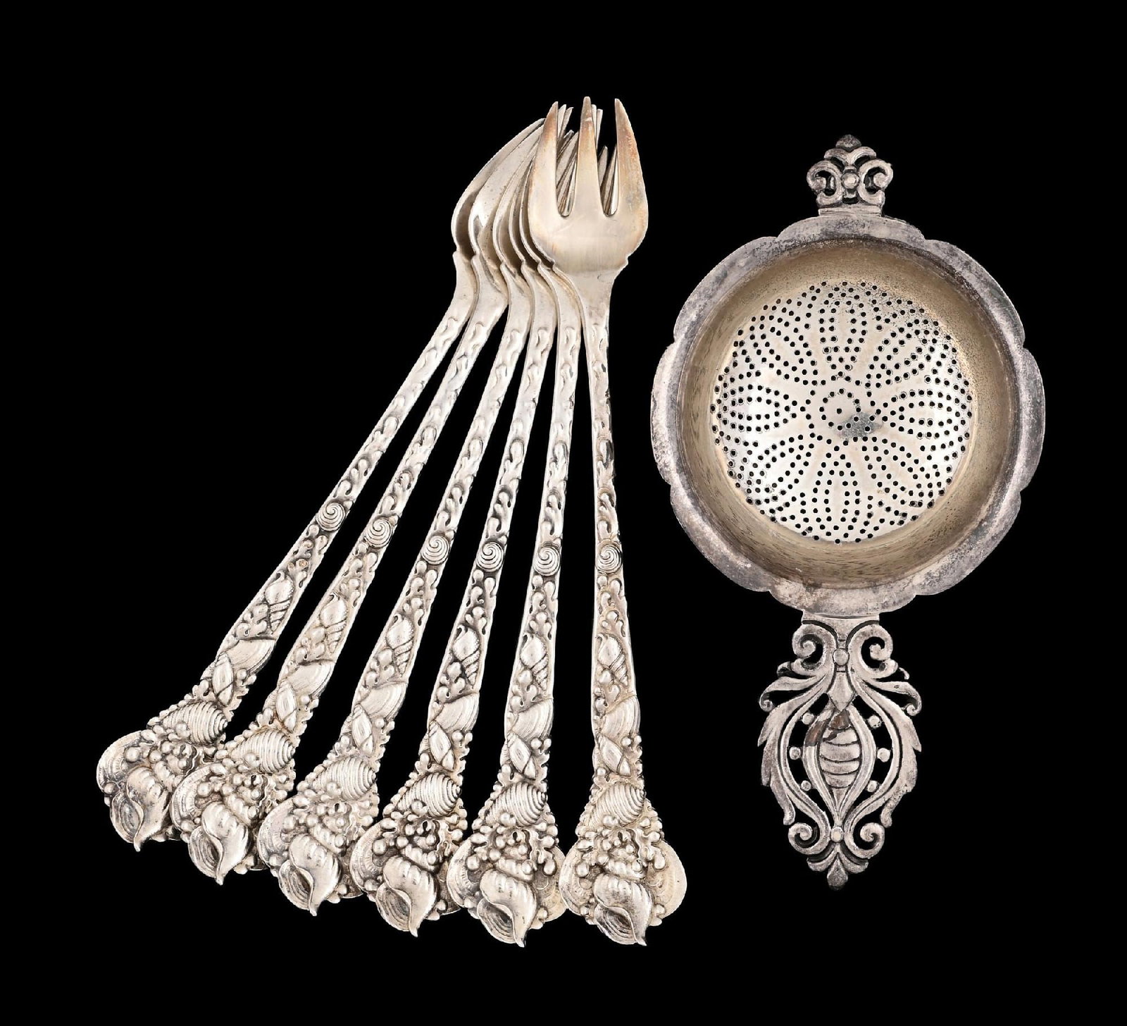 A SET OF SIX TIFFANY STERLING COCKTAIL FORKS: The stems chased with shells and seaweed, and a tea strainer with a pierced floral handle. Length of strainer: 5". Total weight: 8.1 ozt. Condition: Dimensions: