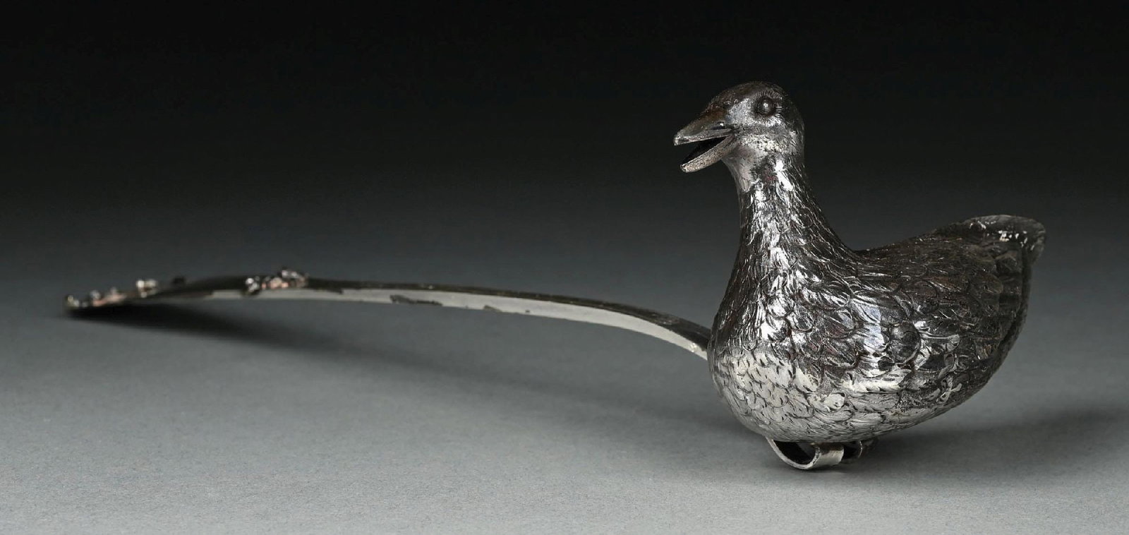 A CONTINENTAL SILVER PUNCH LADLE: The bowl in the form of a duck, chased with feathers and with a spout mouth. Length: 13". Weight: 7.0 ozt. Condition: Dimensions: