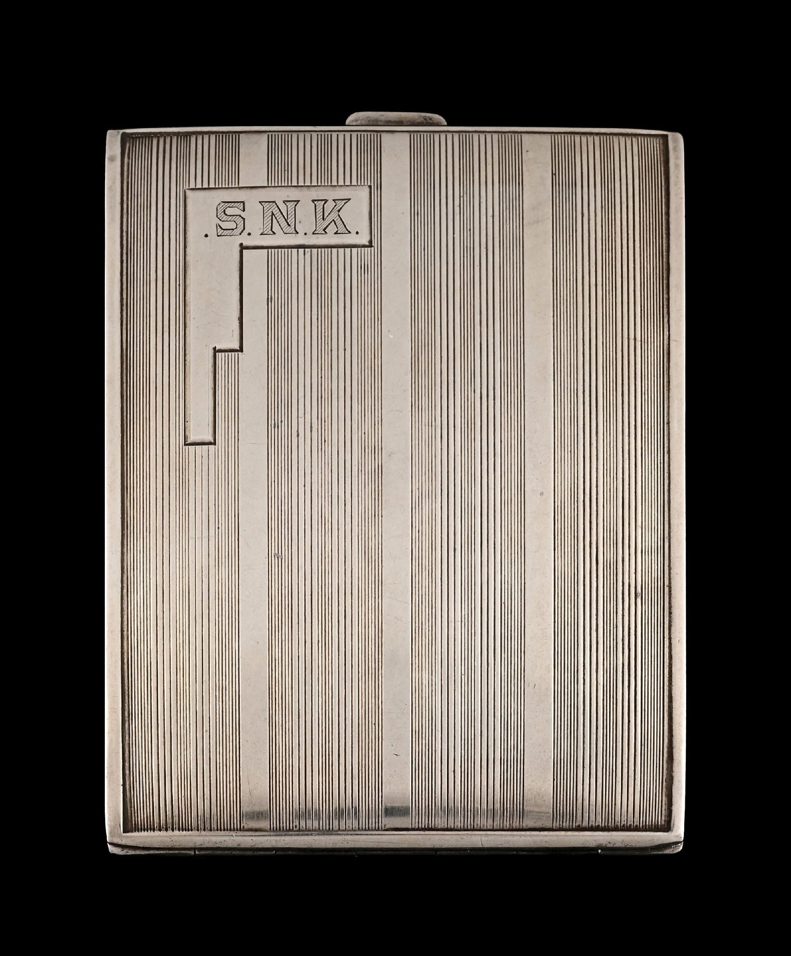 S.N.K CIGARETTE CASE, DATED JULY 18 - 1935: C. 1935. A striking silver-toned cigarette case weighing approximately 100.45 grams, featuring the initials “S.N.K.” on one side and engraved “July 18, 1935.” The interior is m