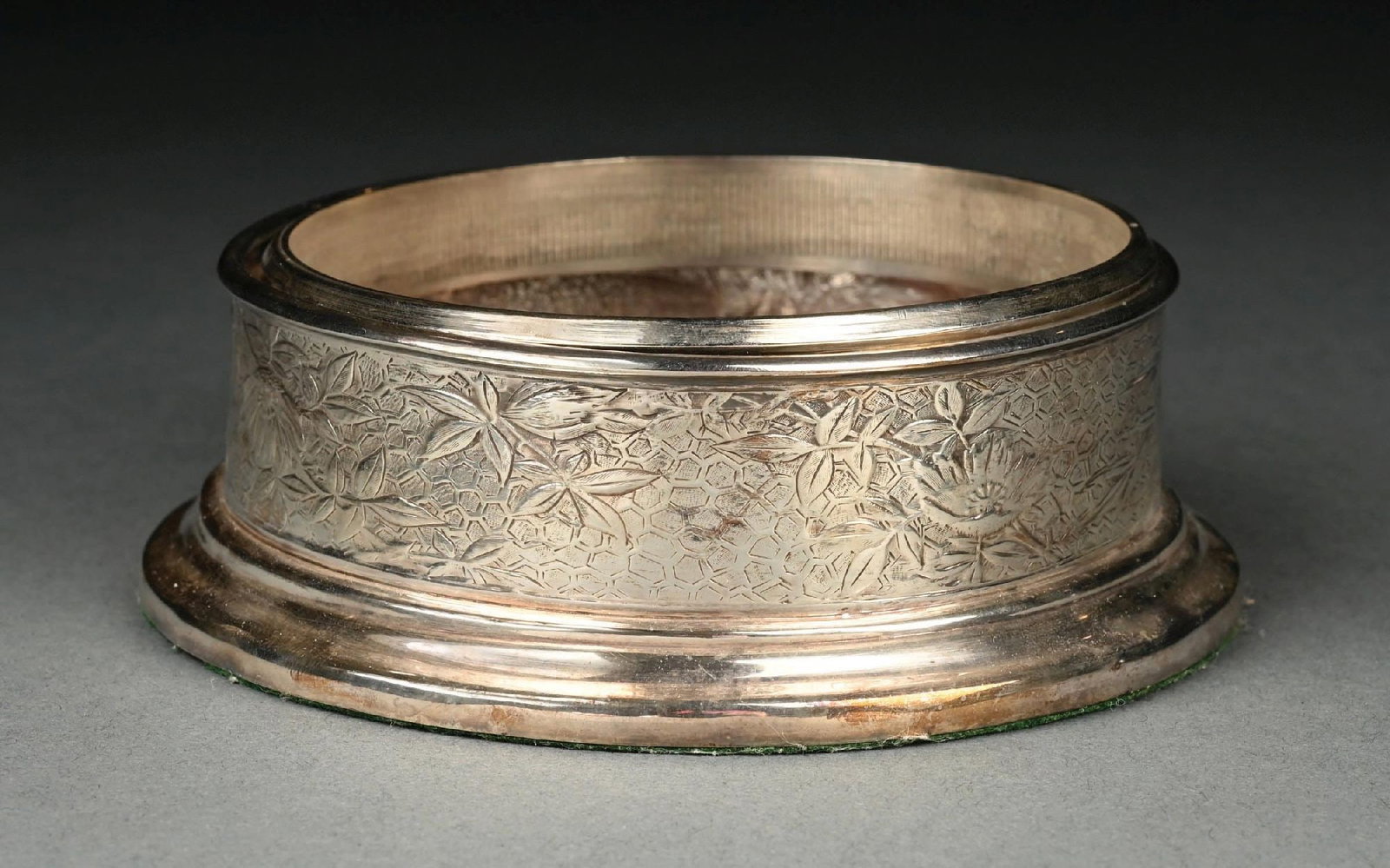 TIFFANY & CO. STERLING SILVER WINE COASTER WITH ROSEWOOD INSERT: A lovely sterling silver wine coaster by Tiffany & Co. The sterling coaster has an etched pattern of flowers, birds, and cobwebs. It has a rosewood insert with a central stamp reading "1999 St. James 